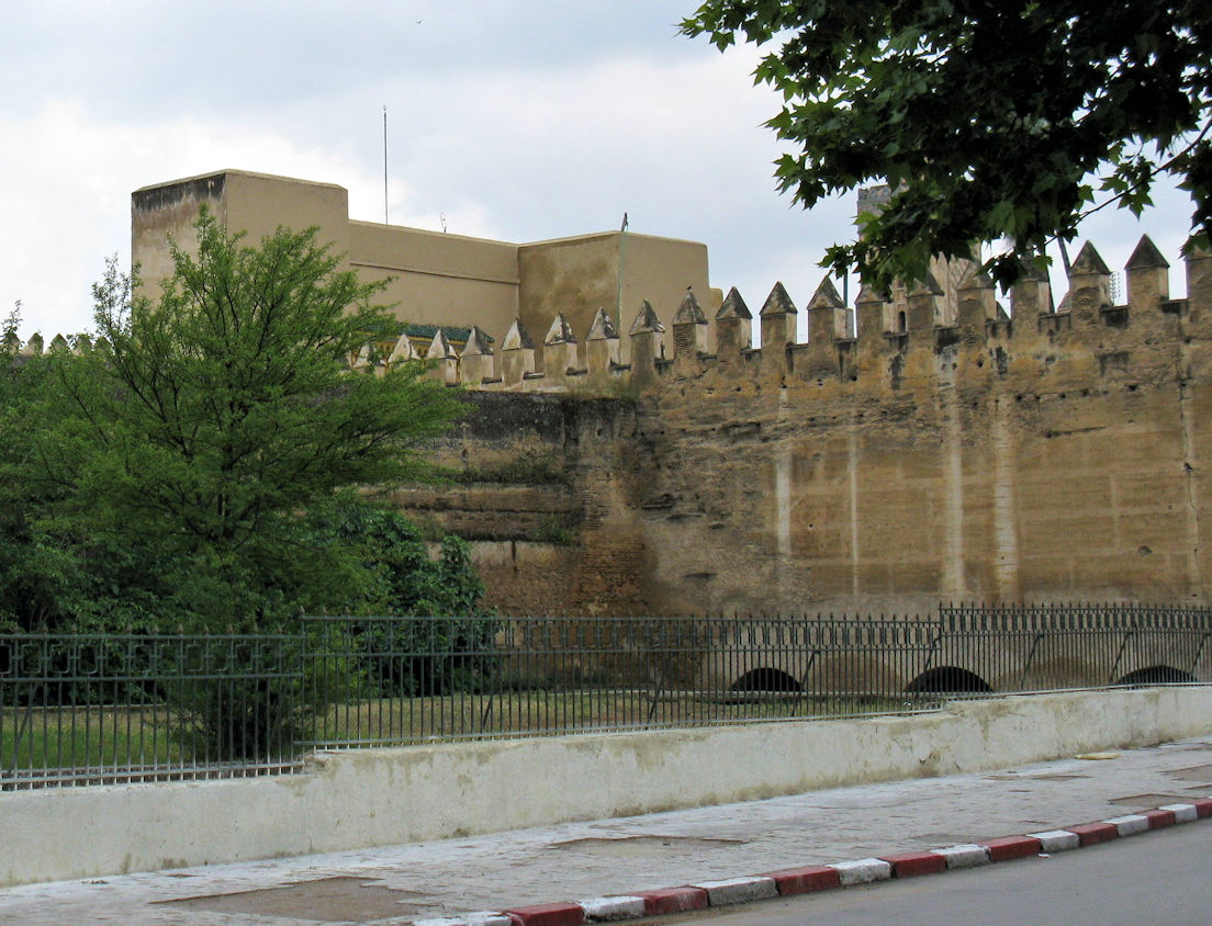 The exterior eastern wall of the Old Mechouar, looking towards the gate of the Dar al-Makhzen (top of the gate is visible above). The semi-circular openings at the bottom of the wall are where the Fez River emerges from its passage under the mechouar.