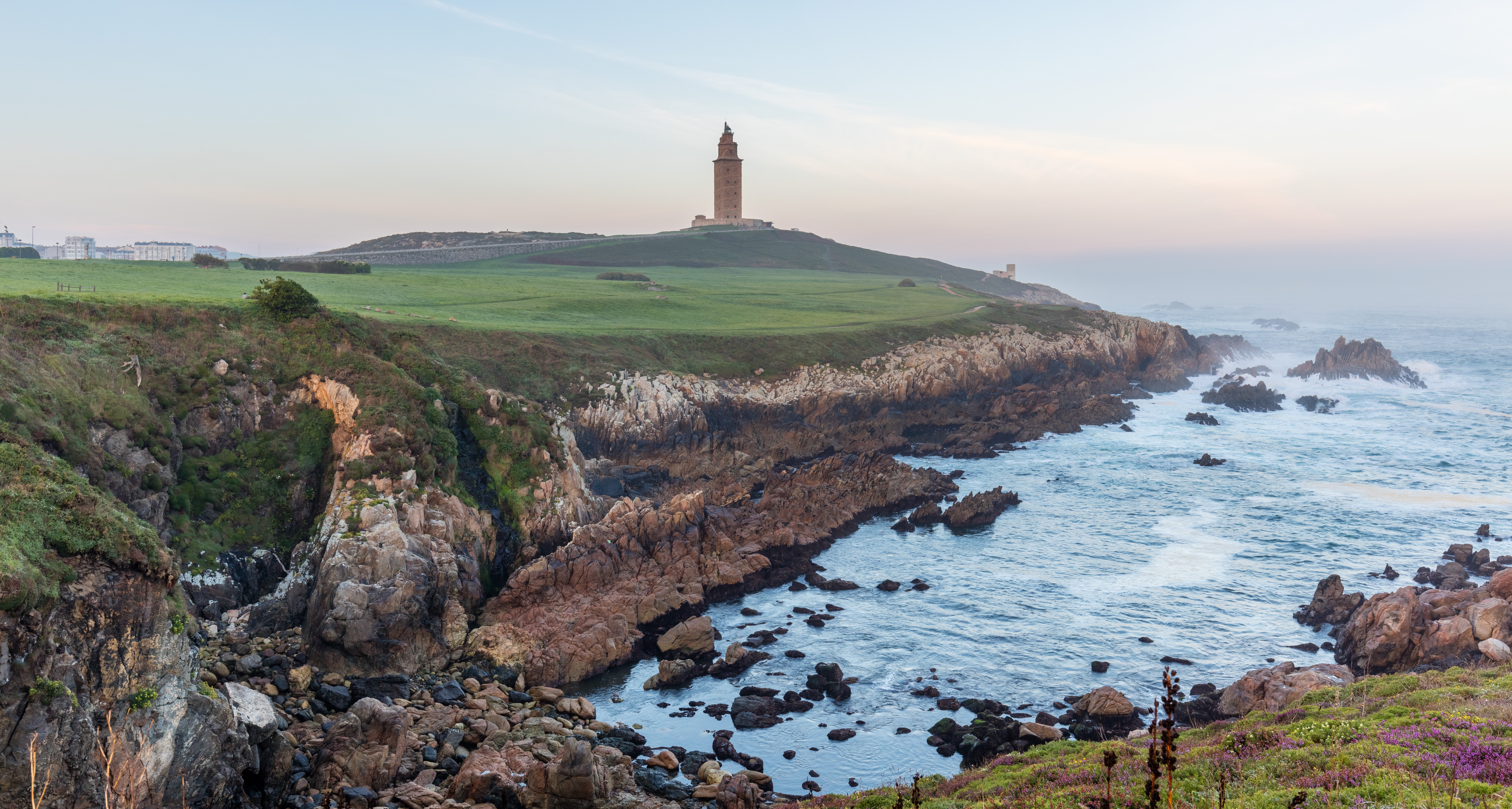 View of the Tower of Hercules and the surrounding area during sunrise. The spot is located near the center of A Coruña, Galicia, north-western coast of Spain. The 55 metres (180 ft) height tower, an ancient Roman lighthouse, is the oldest (almost 1900 years) Roman lighthouse in use today and the second tallest lighthouse in Spain (after the Faro de Chipiona). The lighthouse was rehabilitated in 1791 and is a UNESCO World Heritage Site since 2009.