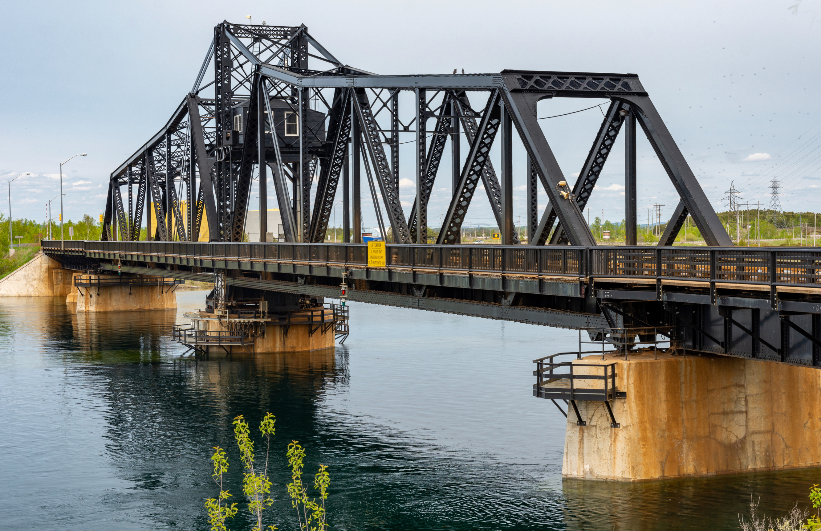 Swing bridge between Manitoulin Island and the mainland, in Little Current, Ontario, was built in 1913 by the Algoma Eastern Railway.  Originally usable only by trains, it was modified in the late 1940s to allow road vehicles also to use it. The rail service was abandoned in the 1980s, and the tracks were removed in the 1990s. This view is from the southwest.