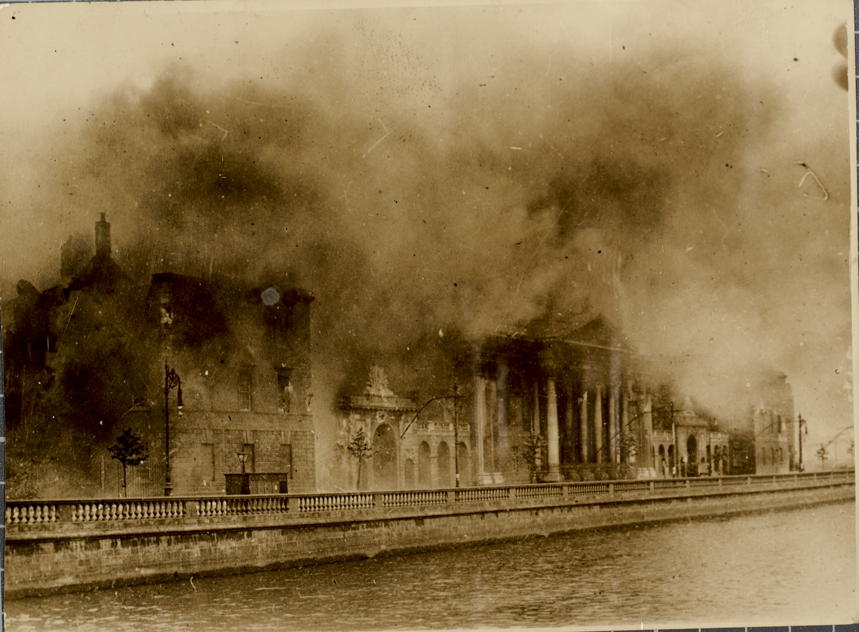 The Four Courts in Dublin during the Battle of Dublin. The building had been taken over by Anti-Treaty forces on the date 14 April 1922. Bombarded by National Army forces on 28 and 29 June, a huge explosion of stored munitions on 30 June destroyed the Public Records Office, and with it a huge swathe of Irish cultural memory.
Date: 30 June 1922

NLI Ref.: HOG57