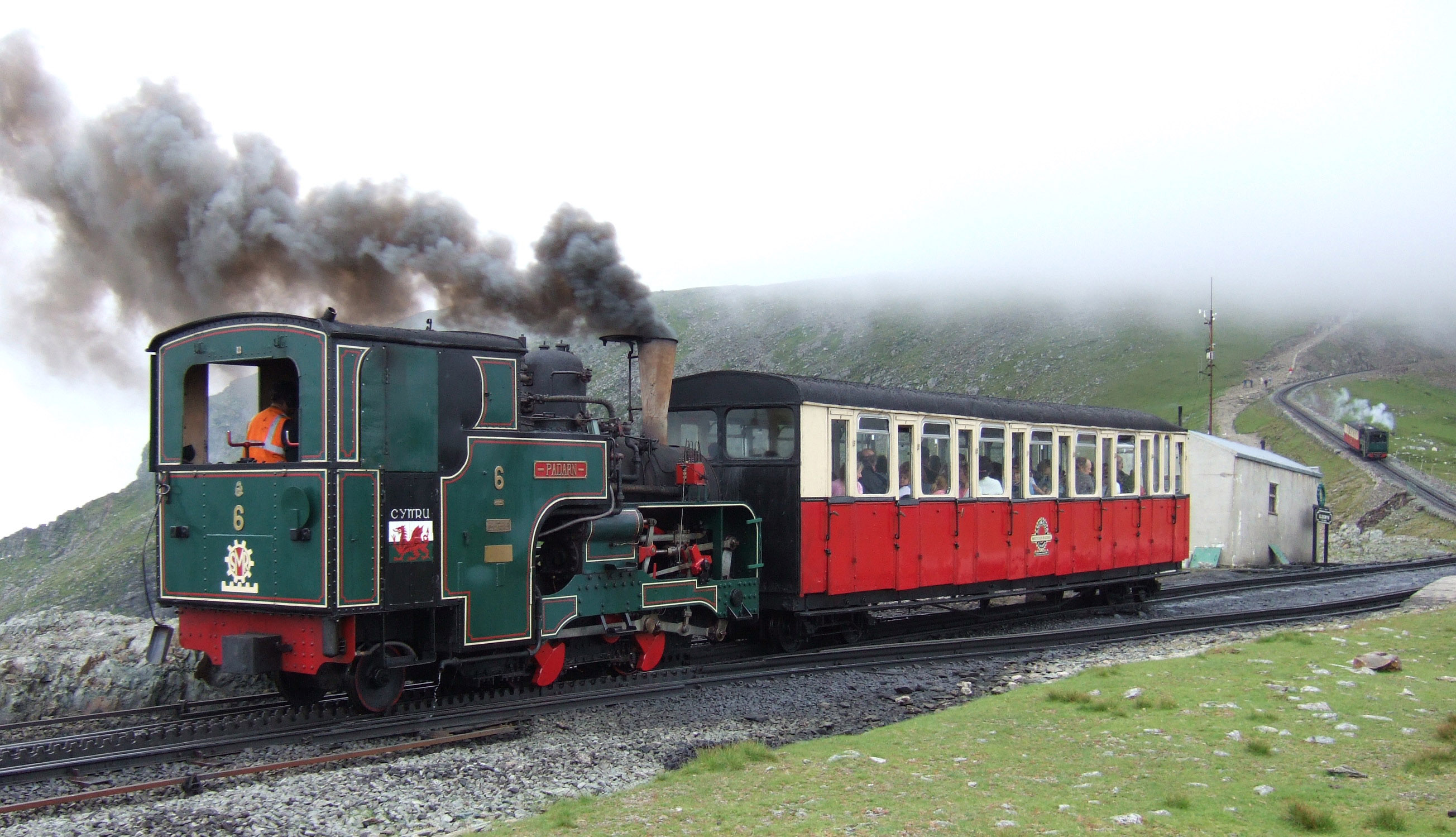 Snowdon Mountain Railway trains pass at Clogwyn. No.6 'Padern' is ascending while No.2 'Enid' is descending out of the clouds. 19th July 2005
Photographer - A.M.Hurrell
Camera - Fuji FinePix F10

Modified - Trimmed and file size reduced using Adobe Photoshop 5.0LE