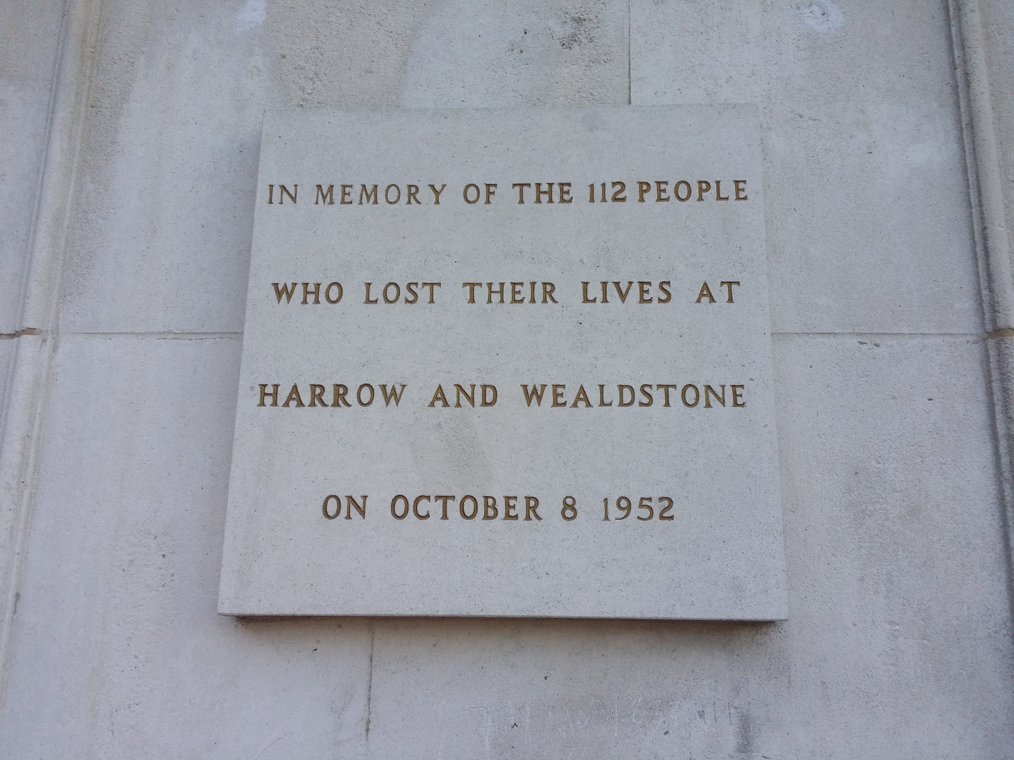 The disaster memorial stone plaque on display at the north-facing entrance of Harrow And Wealdstone railway station.