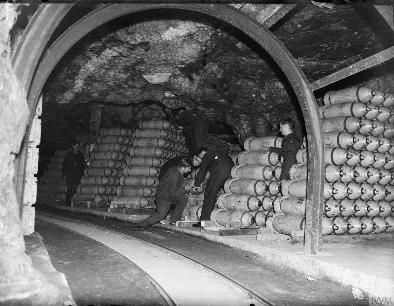 Bombs being stacked in one of the tunnels at RAF Fauld. (Original Imperial War Museum caption: "Storemen stack 250-lb MC bombs in one of the tunnels at No. 21 Maintenance Unit at Fauld, near Hanbury, Staffordshire. RAF Fauld, situated in a former gypsum mine, was the main repository of high explosive ordnance in the country. Part of the MU blew up on 27 November 1944, - the World's largest non-nuclear explosion, - and 70 servicemen and civilian workers were killed or declared missing.")