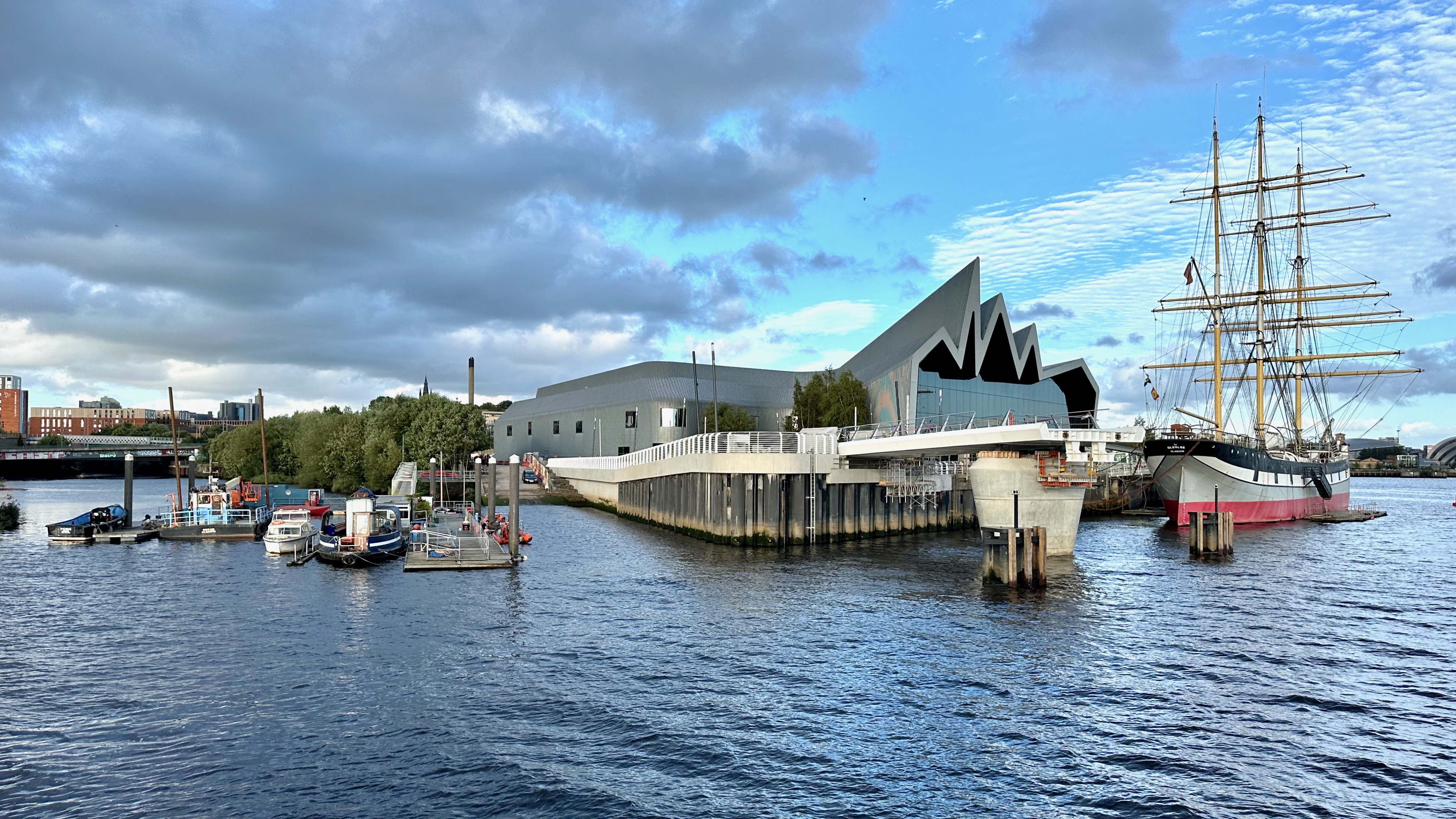 River Kelvin at its confluence with the Clyde, woodland fringes the former Pointhouse shipyard of A. &amp; J. Inglis who built the PS Waverley'. In front of the Riverside Museum; Pointhouse Quay links to the new Govan–Partick Bridge (to be opened to the public in September 2024), and is the permanent berth of tall ship Glenlee. 
Near the centre of the picture, a car stands on a slipway, at the former site of the ferry slip used by the Govan ferry. The original Pointhouse Inn stood nearby. 

Photo taken during trip up the Clyde from Kilcreggan to  Glasgow on PS Waverley.