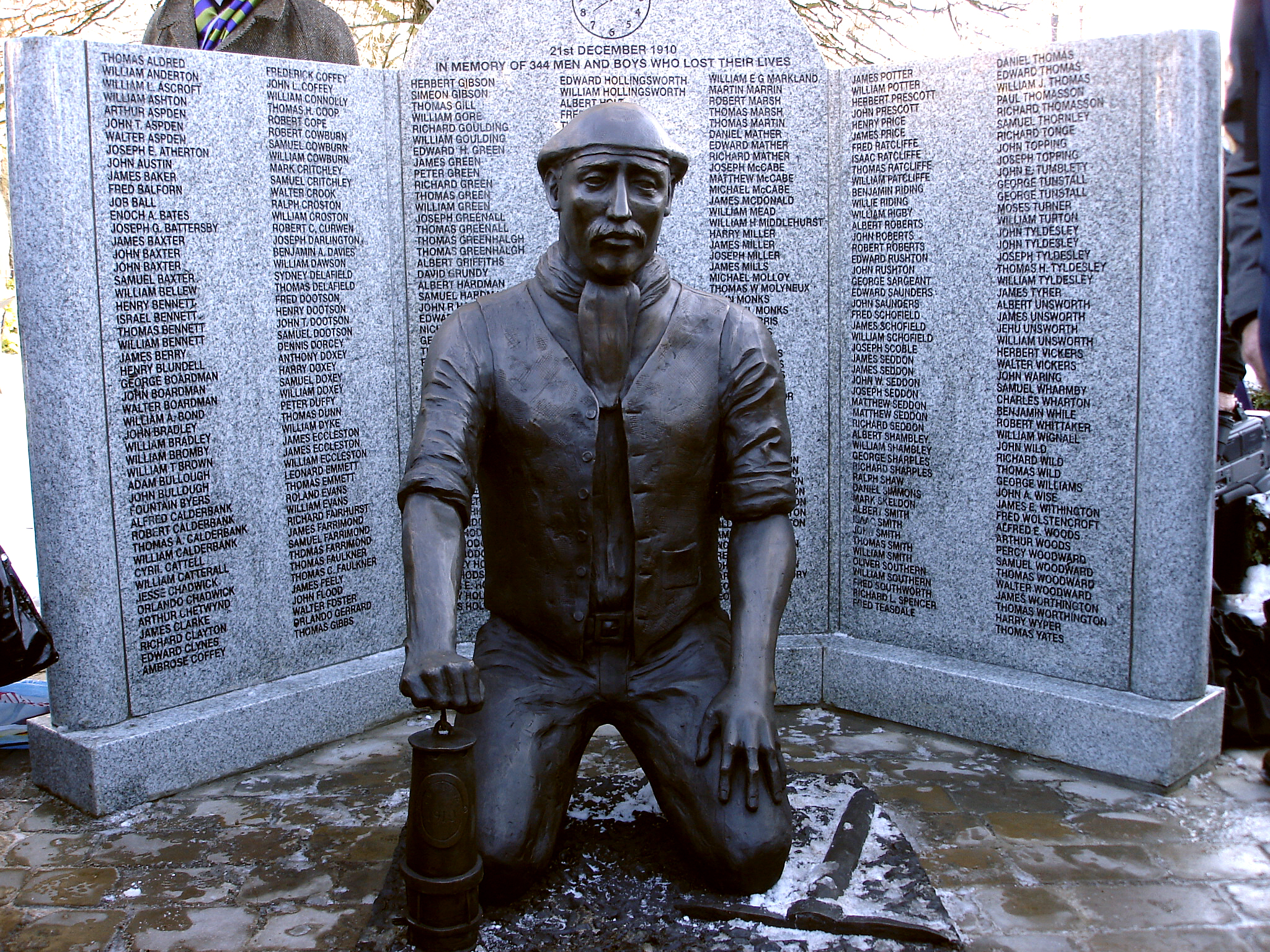 Memorial the victims of the Pretoria Pit Disaster. Bronze statue of kneeling miner in front of granite screen. Sculpture by Jane Robbins.