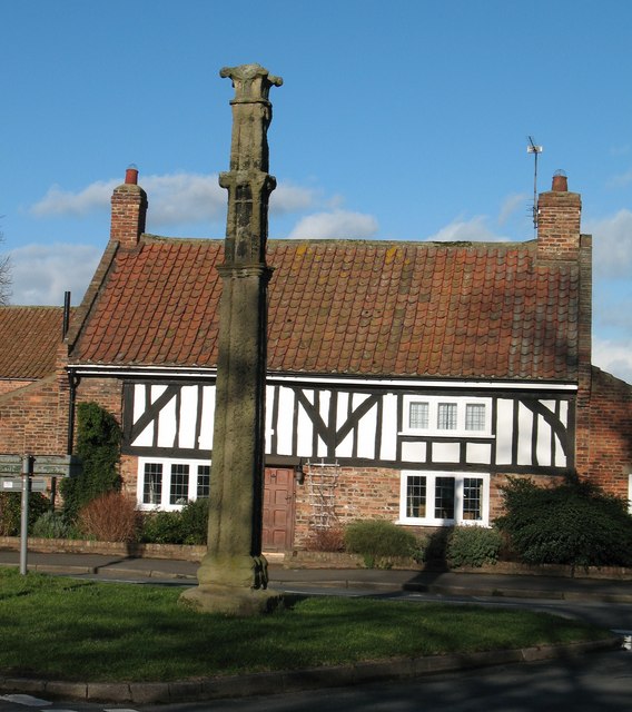 The Battle Cross This cross was moved here from nearby Boroughbridge where it stood in the Market Place until 1852. It commemorates the Battle of Boroughbridge in 1322 when Thomas Earl of Lancaster [who was far too friendly with the Scots] was defeated by Edward II's general, Sir Andrew Harcla. The cottage behind is a typical Vale of York half timbered job and is probably 17thC.