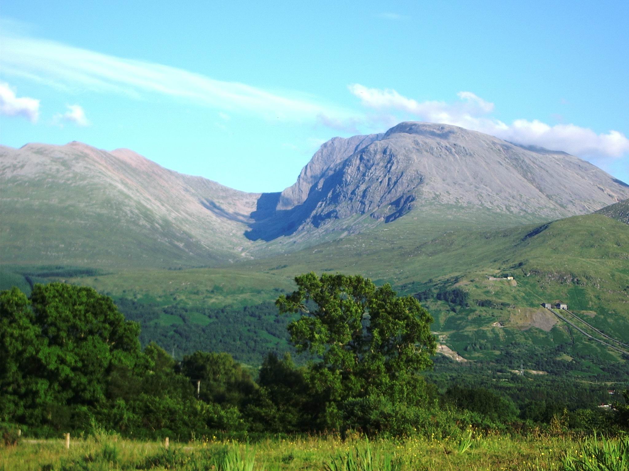 Ben Nevis, 1,344 metres, Scotland. Photograph taken from Banavie about 8 km north west. 18:55, 11 July 2005.  The summit is beyond and to the left of the apparent highest point, Càrn Dearg North, 1,221 metres, (many Scottish mountains are called Càrn Dearg). Càrn Mòr Dearg, 1,223 metres, is to the left, connected to the Ben by the Càrn Mòr Dearg Arête at the head of Coire Leis (slightly in shadow). The pipelines of the Lochaber hydroelectric scheme are visible lower right.
