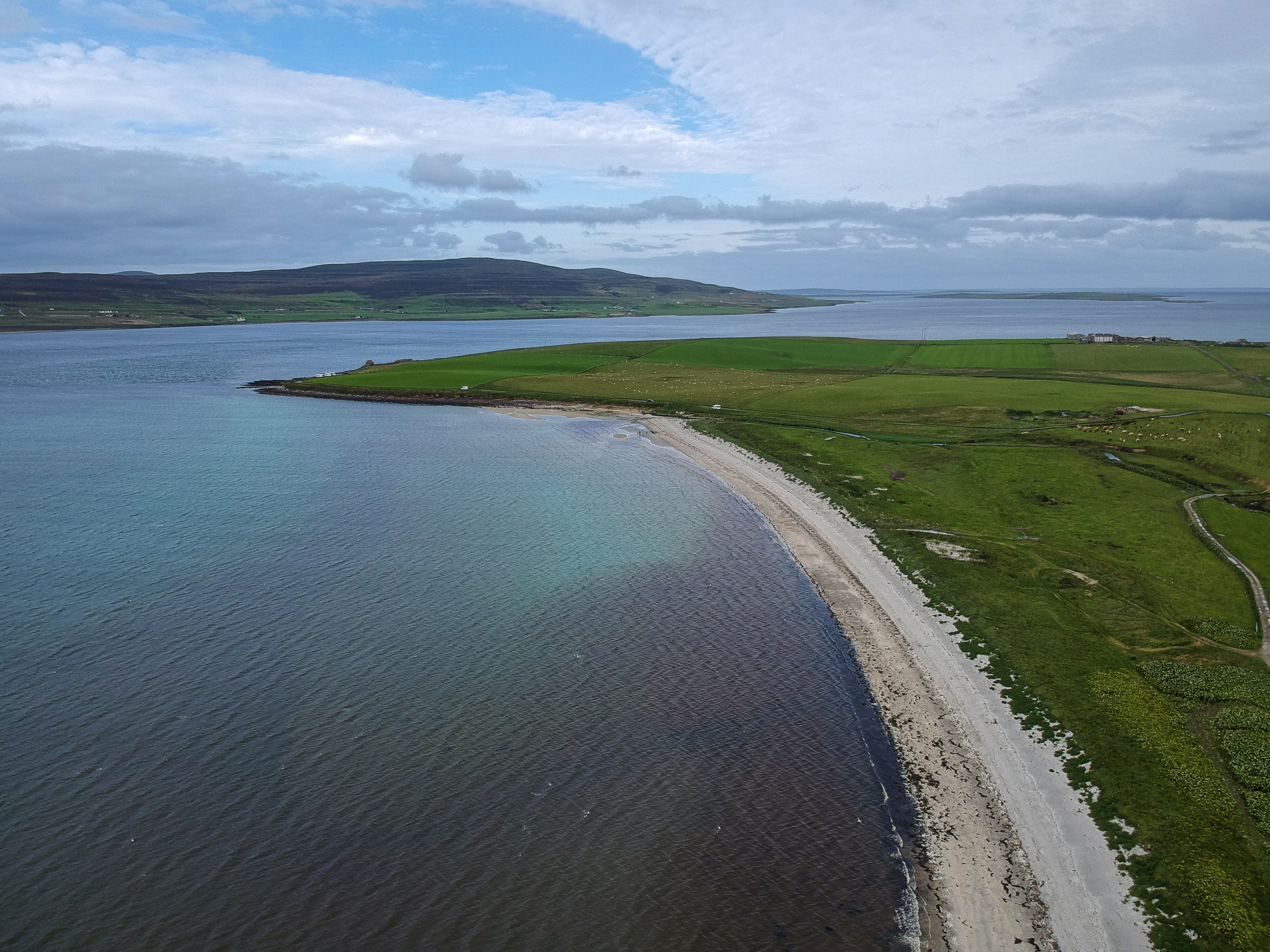 Aerial image of Sands of Evie, a beach near Stenso, Mainland, Orkney. The island of Rousay is visible in the background, as is the Broch of Gurness.