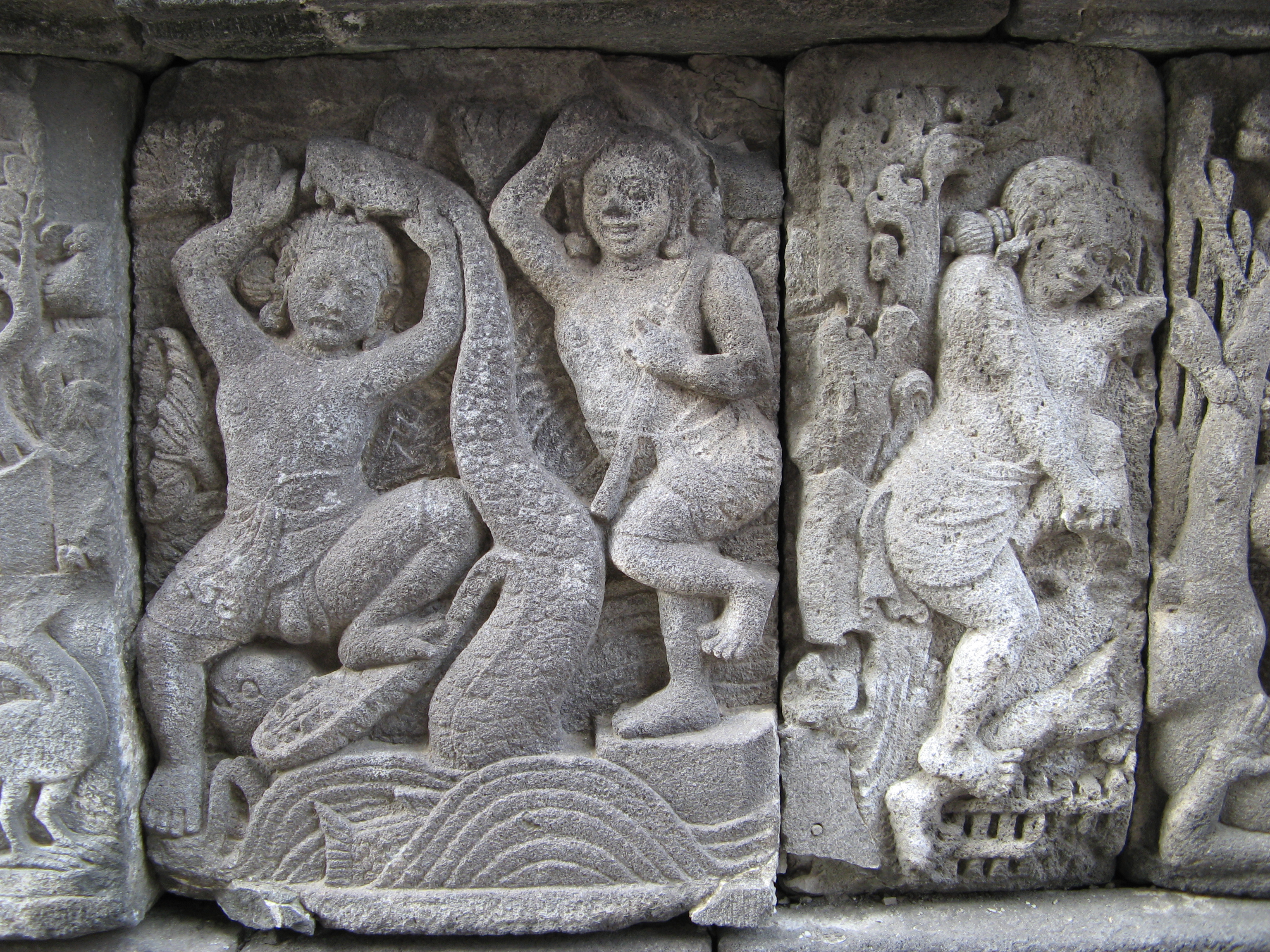 In this panel from the Vishnu temple of Prambanan, Balarama - Krishna's brother - is prying apart the jaws of Kaliya, a poisonous snake who had been infesting Krishna's childhood pond on the Jamuna River, while Krishna dances in triumph.