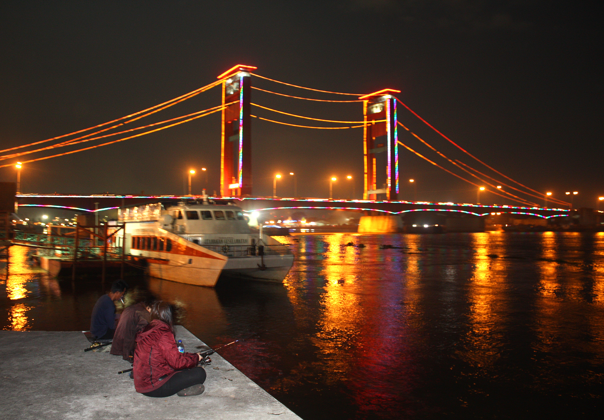 Some men doing night fishing on the bank of Musi river by the Ampera Bridge. The bridge is a major landmark in Palembang, Indonesia. It was constructed in 1962-1965.