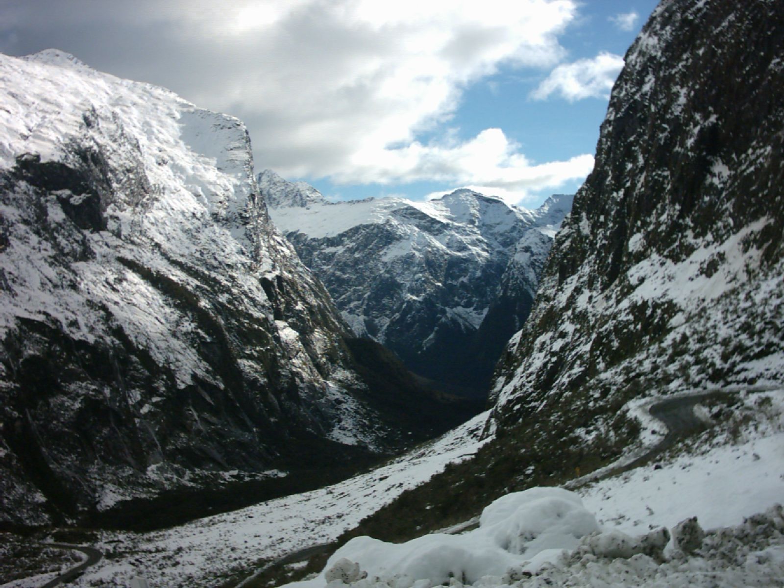 Looking west from the portal of the Homer Tunnel (underneath Homer Saddle) into one of the valleys (Cleddau Valley) leading into Milford Sound, New Zealand. Contrast between early-winter snow white and rain-slick, dark rock.