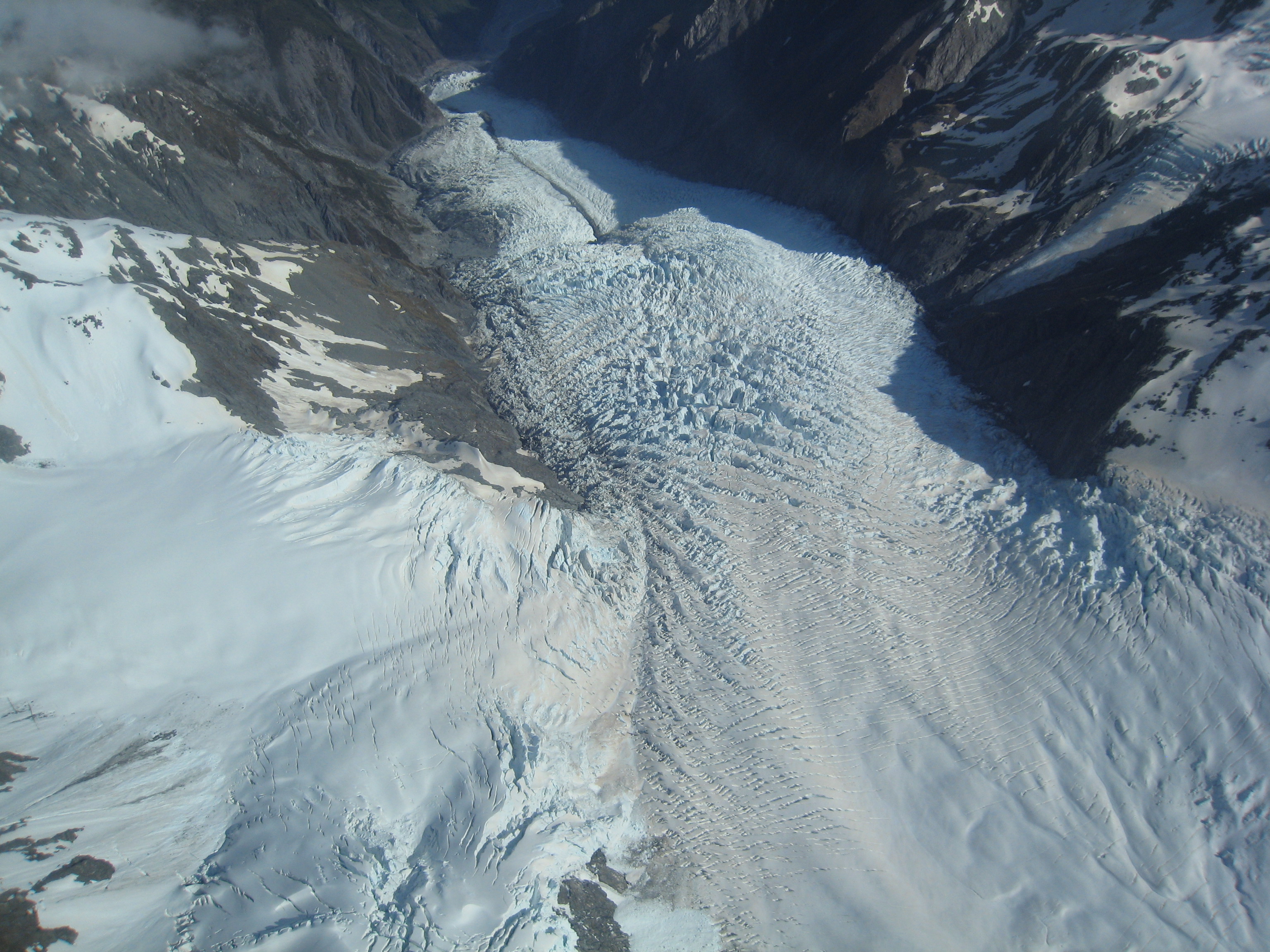 Aerial view of the Franz Josef Glacier, looking down its length from above the tributary Melchior Glacier. On the far side of the valley, the small glacier that does not quite meet the Franz Josef is the Almer Glacier.
