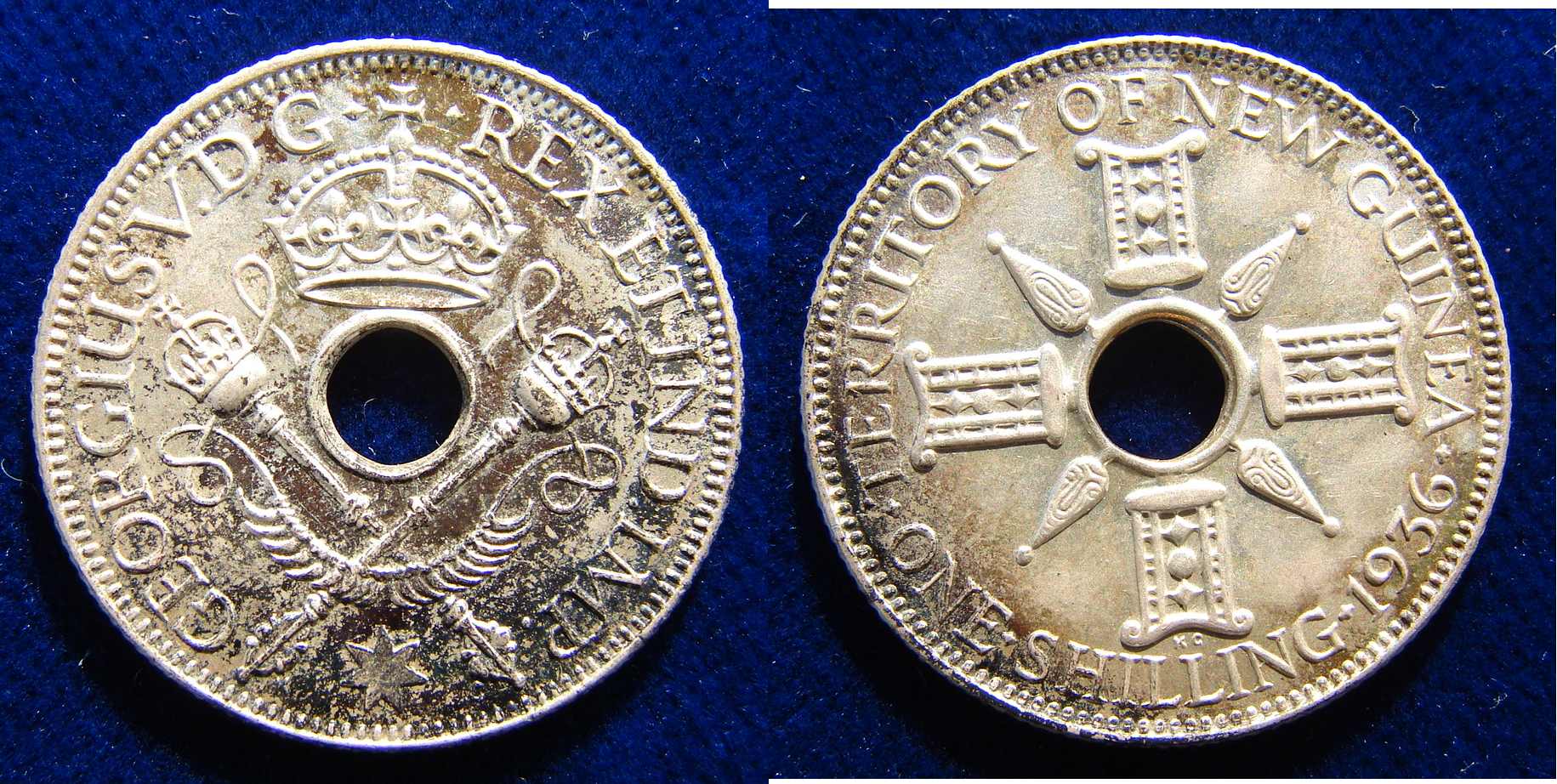5.4 g Sterling Silver
George V, 1921- 1936
Hole in centre, flanked by crossed sceptres and crownabove Around: "* GEORGIUS V. D G REX ET IND. IMP. *"/ On the reverse the hole is flanked by indigenous designs, around: "TERRITORY OF NEW GUINEA ONE SHILLING date". KM 5
Medallist: KG (George Kruger Gray), 1880 London - 1943 Chichester, England.


Condition: Nicely toned EXTREMELY FINE.