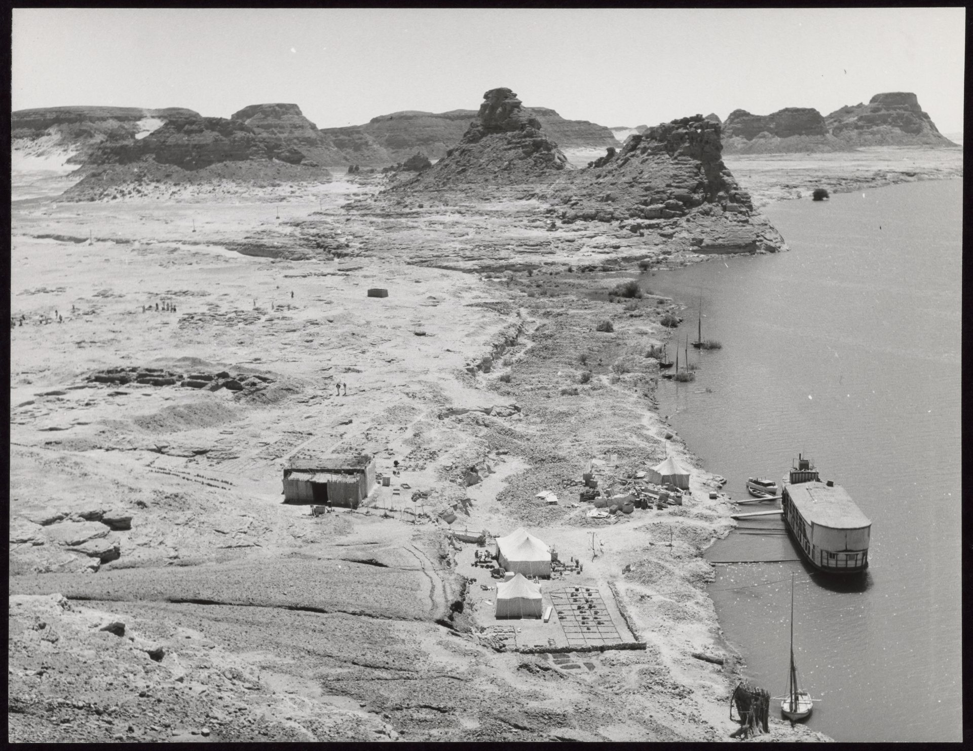 Aerial view of the site of the American Research Centre's archaeological expedition at Gebel Adda. The dark cavities to the left are the excavations of an early Christian cemetery. An ancient course of the Nile ran through the cliffs in the background.