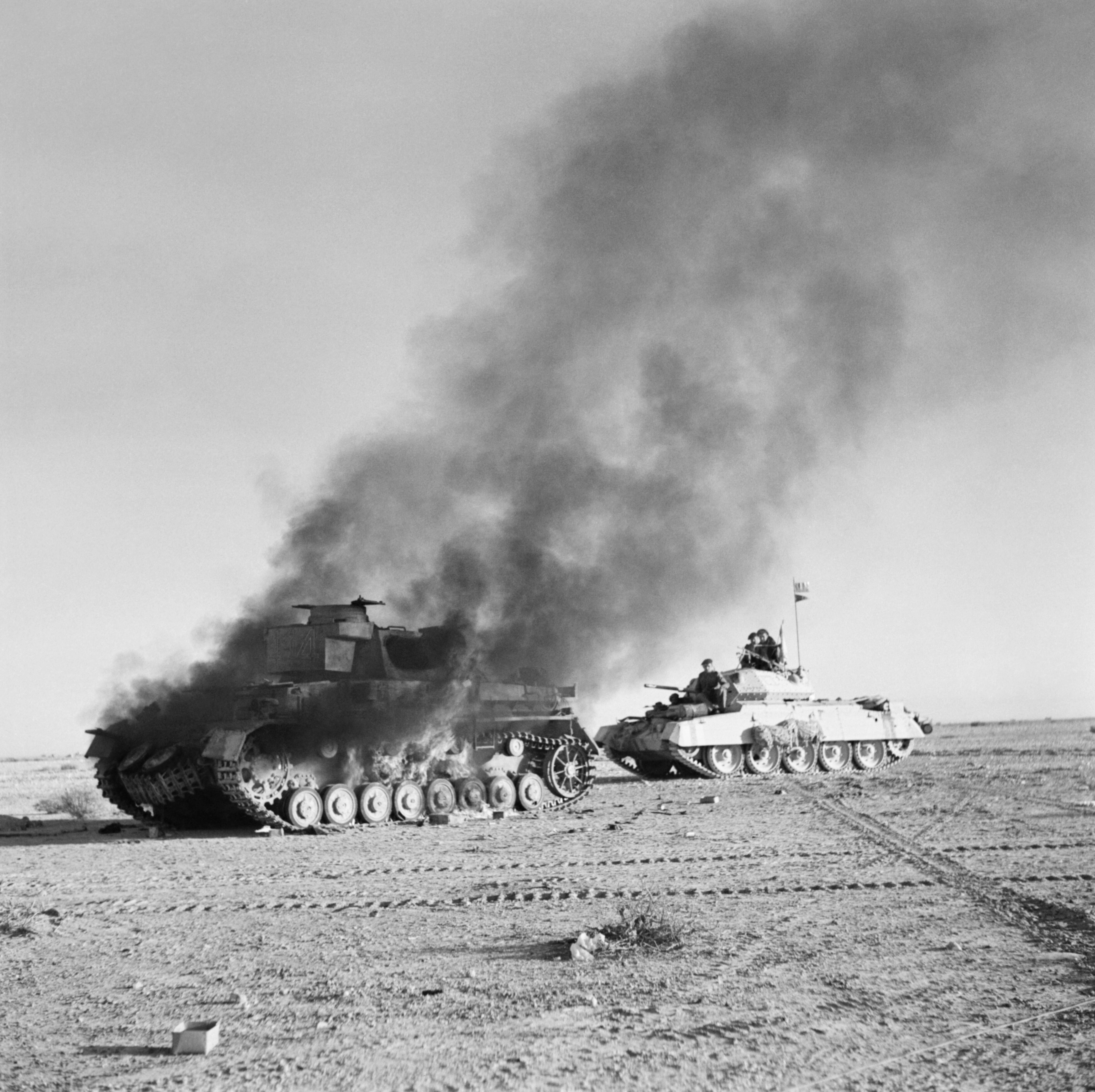 British Crusader tank passes a burning German Panzer IV tank during Operation Crusader