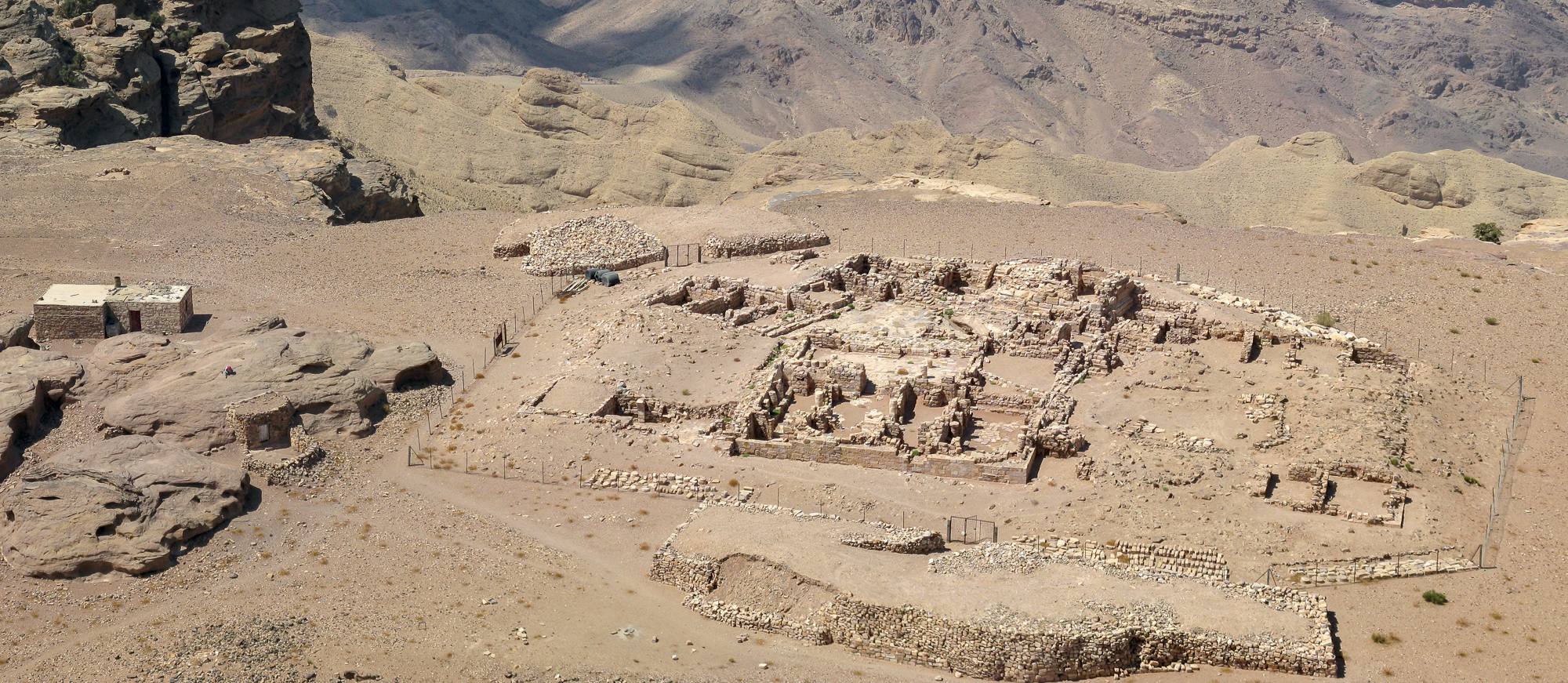 Excavations of Byzantine church ruins near Mt. Aaron, Jordan, as seen from the top of the mountain, with a police or guard post and a Bedouin hut on the left side.