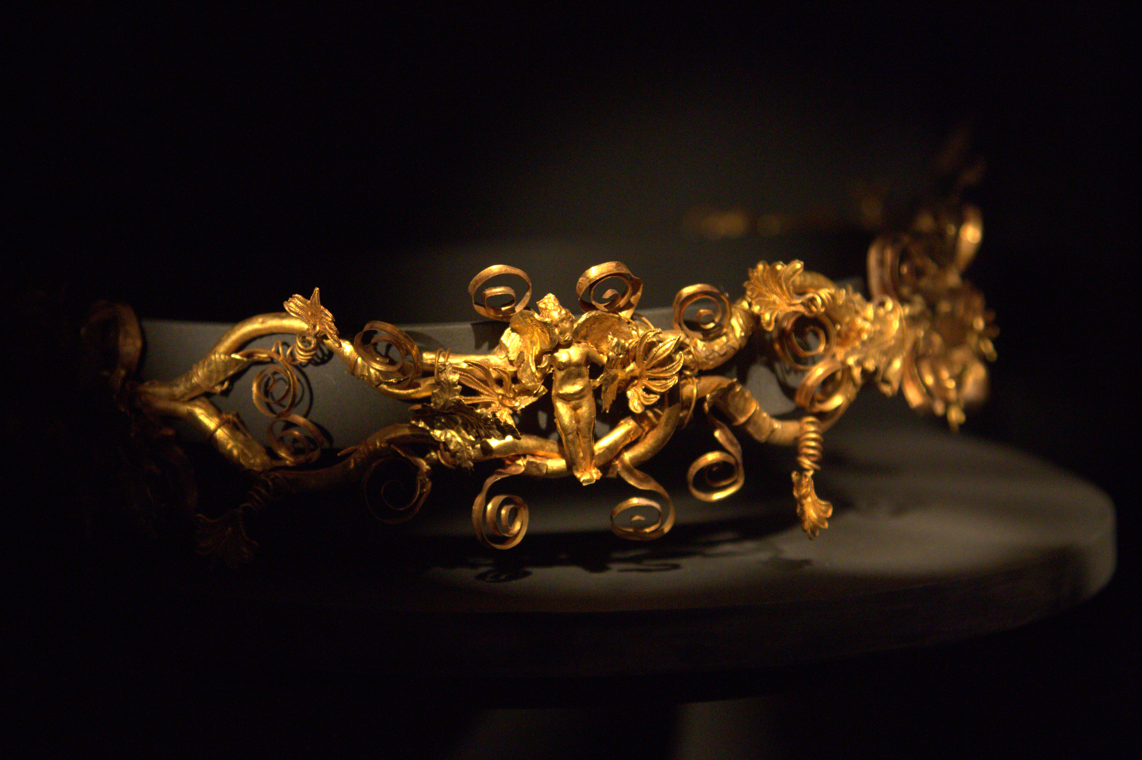 At the center a "knot of Heracules" on which is a winged Eros holding doves in his hands. Grave good from tombs at Sedes. 320-300 BC.
Archaeological Museum of Thessaloniki, Greece.
---
Χρυσό διάδημα που αποτελείται από οκτώ λυρόσχημα τμήματα που διακοσμούνται με φύλλα άκανθας, έλικες και ανθέμια. Στο κέντρο σχηματίζεται "κόμβος του Ηρακλή" όπου παρά φτερωτός Έρωτας με περιστέρια στα χέρια.

Αρχαιολογικό Μουσείο Θεσσαλονίκης.