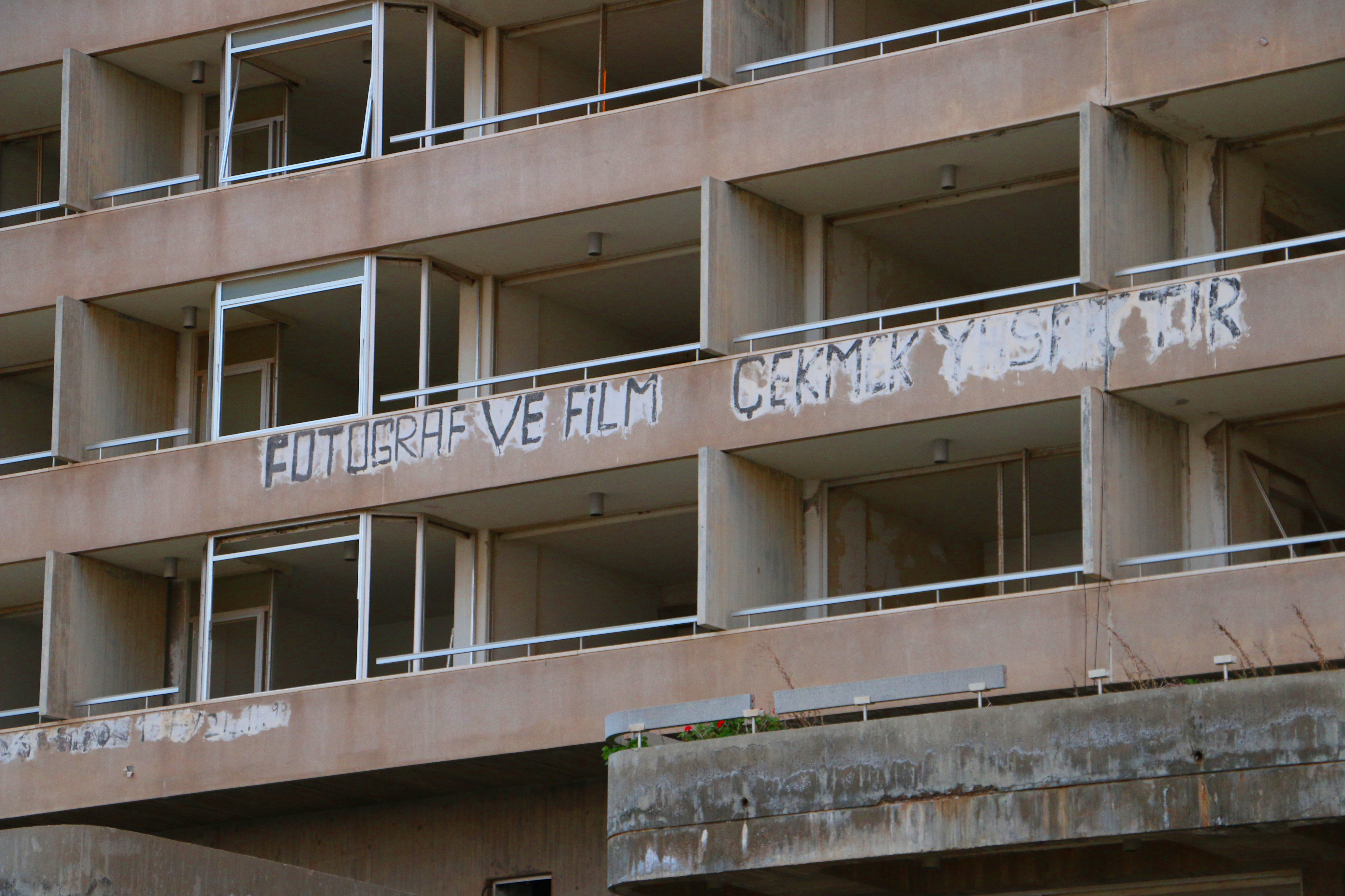 Part of a hotel front in the Varosha Ghost Town, Famagusta CYPRUS. 
The tourist resort town was abandoned in 1974 after the Turkish Army captured most of Famagusta. This area was fenced off and never officially inhabited after the war, unlike the rest of Northern Cyprus. 

Painted on the exterior is a warning that "taking pictures or filming this is prohibited", written in Turkish.