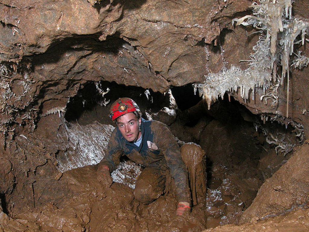 Photo by Dave Bunnell of a caver traversing a muddy crawlway in Black Chasm Cavern.
A National Natural Landmark of the United States in Amador County, California.