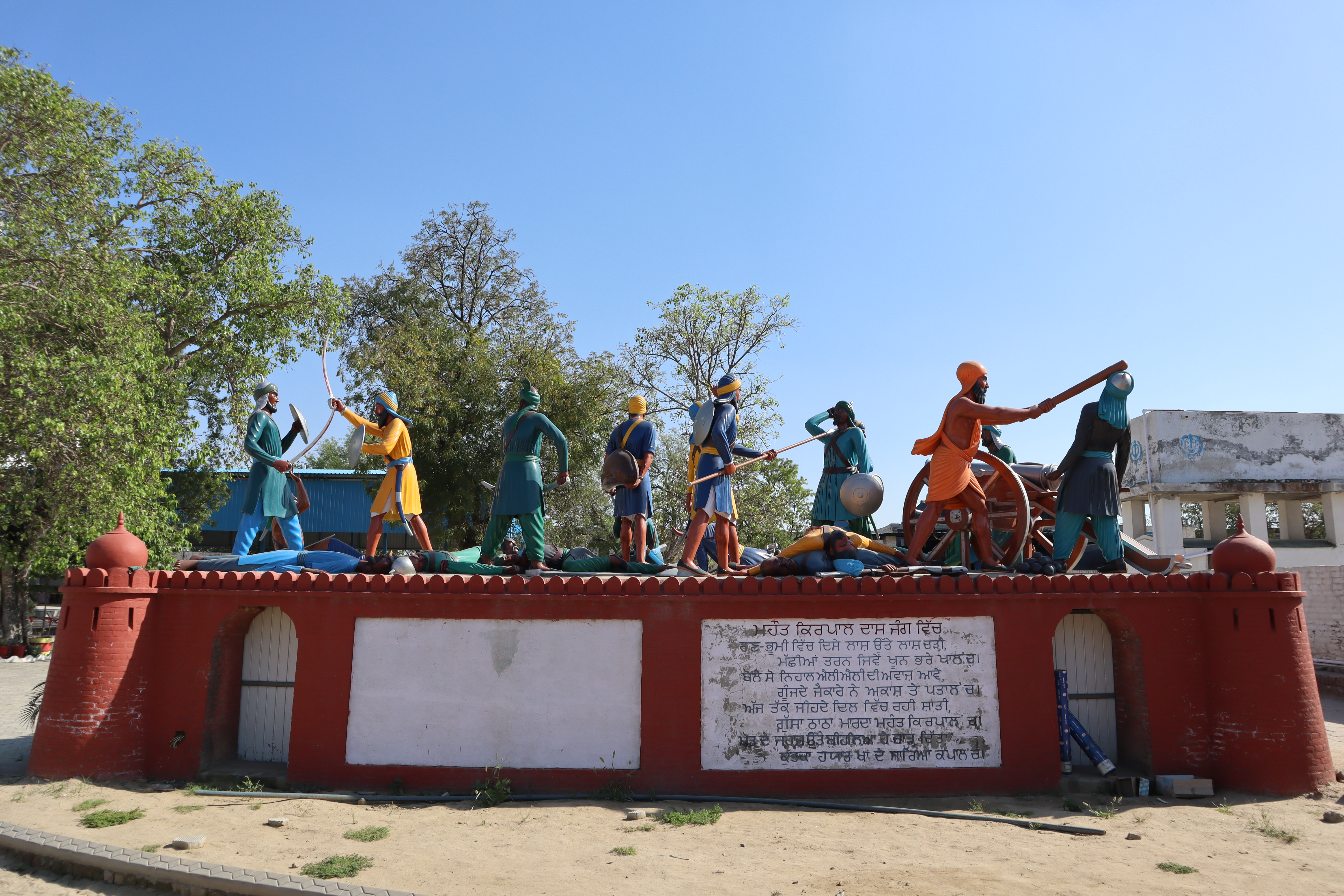 Diorama sculptural monument of Mahant Kirpal Das in-combat during the Battle of Bhangani, Gurdwara Mehdiana Sahib, Mehdiana, Ludhiana district, Punjab, India, 9 April 2023 (time is per Eastern Standard Time for Ontario, Canada as I forgot to change the time-setting on my camera before setting-off on my trip to India). The date of this photo, 9 April 2023, fell during the lead-up to Vaisakhi (celebrated on April 14th in 2023). Vaisakhi is one of the most significant festivals in Sikhism, marking the birth of the Khalsa. It is common for major Gurdwaras in Punjab to host week-long festivities, including Nagar Kirtans (processions), community meals (Langar), and carnival-style setups (Mela).
Gurdwara Mehdiana Sahib, also called the ‘School of Sikh History', is a Sikh gurdwara located in the village of Mehdiana, just outside Manuke, near Jagraon in Ludhiana district, India. Gurdwara Mehdiana Sahib is unique for featuring a display of diorama figures/statues depicting scenes from Sikh history. Baba Jora Singh (Lakha) was the custodian of the gurdwara from . Iqbal Singh Gill, an artist based in Nihal Singh Wala, was one of the artisans who made the statues for the gurdwara.
Other artisans who contributed to making the sculptures and paintings for the gurdwara are as follows: M/ S. Mohan Singh Malla, Karam Singh Manukey (Meenakari), Bhajan Singh Bhamipura, Sukhvinder Singh Bhamipura, Shamsher Singh Lakha, Kulwant Singh Manukey, Bhola Singh, Joginder Singh Raikoti, Jaswant Singh, Bant Singh Burjkalala, Ganga Singh Sherpura, Mistri Joginder Singh, Mohinder Singh Basrawa, Ajit Singh Sairon, etc. 
Further info/reading: [1]; [2]; [3]; [4]; [5]


It is believed that Guru Gobind Singh rested and bathed at adhab (natural water-body, such as a pond or small lake) in the vicinity of the present-day complex, with the dhab itself being transformed/expanded into a sarovar (temple-tank) by later renovators. After Guru Gobind Singh's visit in 1705, the site at Mehdiana retained its historical association but experienced negligible formal development for over two centuries, devolving into an overgrown, forested area with sparse maintenance and no nearby settlements within 2-3 miles by the late 1960s. In 1972, Jathedar Jora Singh Lakha took charge of the Gurdwara's management and spearheaded its transformation, expanding the complex from a few acres to 25 acres (100,000 m²) through substantial investments, including crores of rupees for construction in traditional Sikh architectural style with intricate meenakari work. 
In the 1970s, Jathedar Jora Singh Lakha initiated major developments at Gurdwara Mehdiana Sahib, expanding the site from an underdeveloped, forested area lacking nearby habitation into a 25-acre complex focused on preserving and educating about Sikh history. Key enhancements included the construction of a modern sarovar, whose foundation was laid by Sadhu Singh Bhora, and the establishment of a museum displaying paintings of Guru Gobind Singh's journeys across the Malwa region. The complex saw further upgrades with the addition of life-size sculptures and statues illustrating Sikh martyrdoms, battles, and historical figures, such as those depicting executions under Mughal rule, to serve as visual aids for visitors. Architectural improvements featured intricate meenakari enamel work and engravings on the main shrine and surrounding structures, while ancillary facilities like a mini zoo, 24-hour langar hall, and Baba Farid's asthan with additional sculptures were incorporated. In the late 1980s, renovations under Jathedar Jora Singh Lakha's oversight solidified the site's role as a pilgrimage and educational hub, including the founding of Dasmesh Public School.
The Gurdwara Mehdiana Sahib is privately owned and managed, having been developed by Jathedar Jora Singh Lakha from the late 1960s onward, with the complex expanding to 25 acres by 1972. Visitors encounter an immersive educational environment centered on the site's extensive sculptures and dioramas illustrating Sikh martyrdoms and pivotal events, reinforcing its designation as the 'School of Sikh History'. Supporting facilities enhance the visitor stay, including a museum housing artifacts, a small library for historical texts, a mini zoo, and an on-site Dasmesh Public School serving approximately 500 students, which integrates community education with religious observance. Portions of the premises offer wheelchair accessibility.
Terminologies:
1. Itihasak Butt (Historical Statues/Sculptures): In Punjabi, these figures are often called Butt (statues) or Murtiya (sculptures), though "Butt" is the more common conversational term in this context. They are almost all life-sized and were created to make history tangible for those who cannot read the scriptures or historical texts.
2. Shaheedi Sakas (Martyrdom Narratives): Many of the dioramas depict Shaheedi (martyrdom). These specific displays are often referred to as Shaheedi scenes.
3. Ajaibghar (Museum Context): While the displays are spread across the 25-acre park-like complex, the collection as a whole is often described as an Open-Air Museum or Sikh Ajaibghar.
4. Jathedar Jora Singh Lakha: The visionary who transformed the site from a forest into this educational complex starting in 1972.

5. Iqbal Singh Gill: The primary artist/sculptor responsible for many of the life-sized figures.