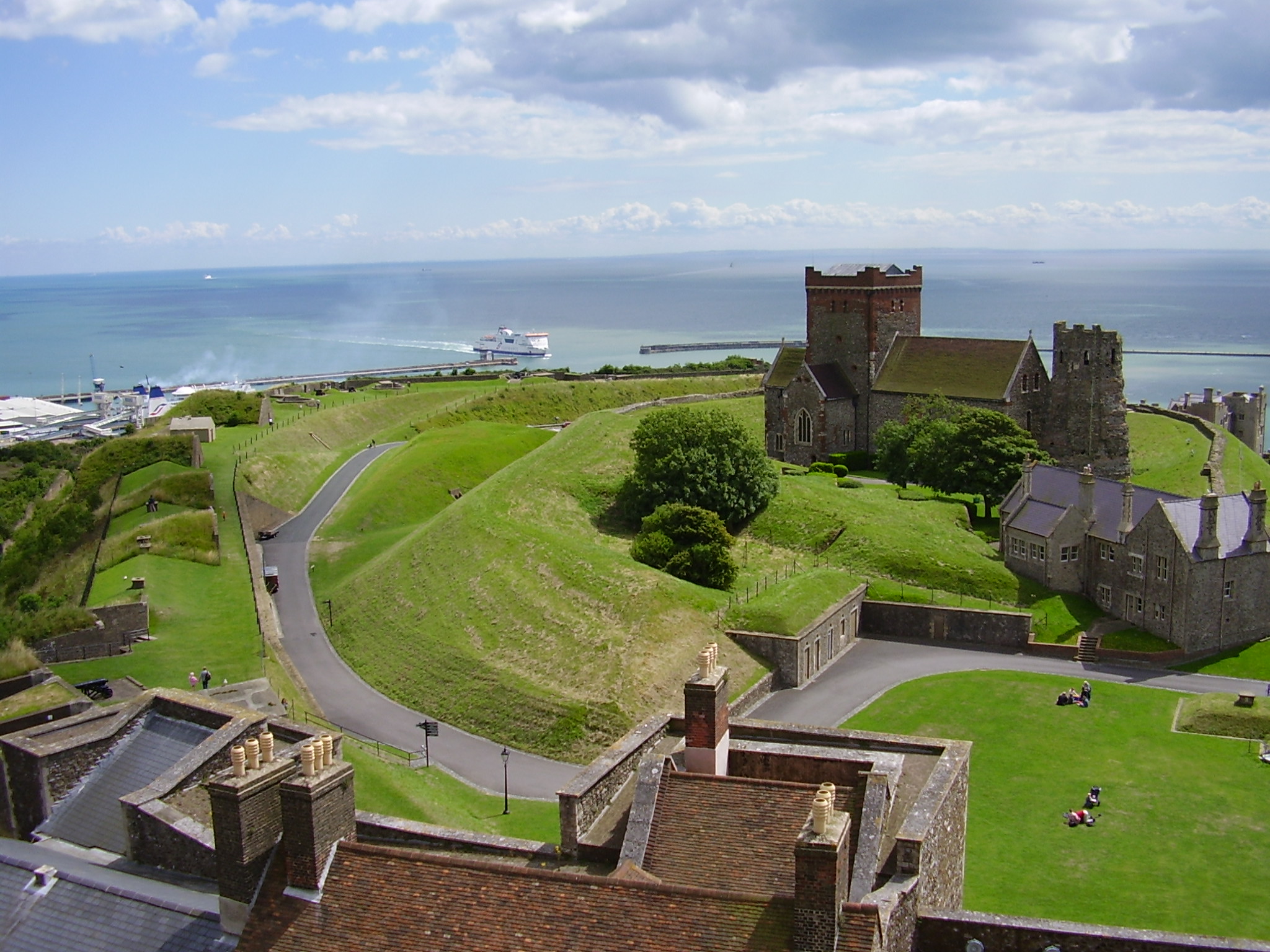 Church of St Mary in Castro in the grounds of Dover Castle, Kent, south coast of England, overlooking the English Channel. The church was built next to the remains of a Roman lighthouse, here seen to the right of the church, which was used as the church's bell-tower. A ship - probably a Channel ferry - can be seen coming into to the port of Dover. (Description by JackyR from local knowledge plus English WP article)