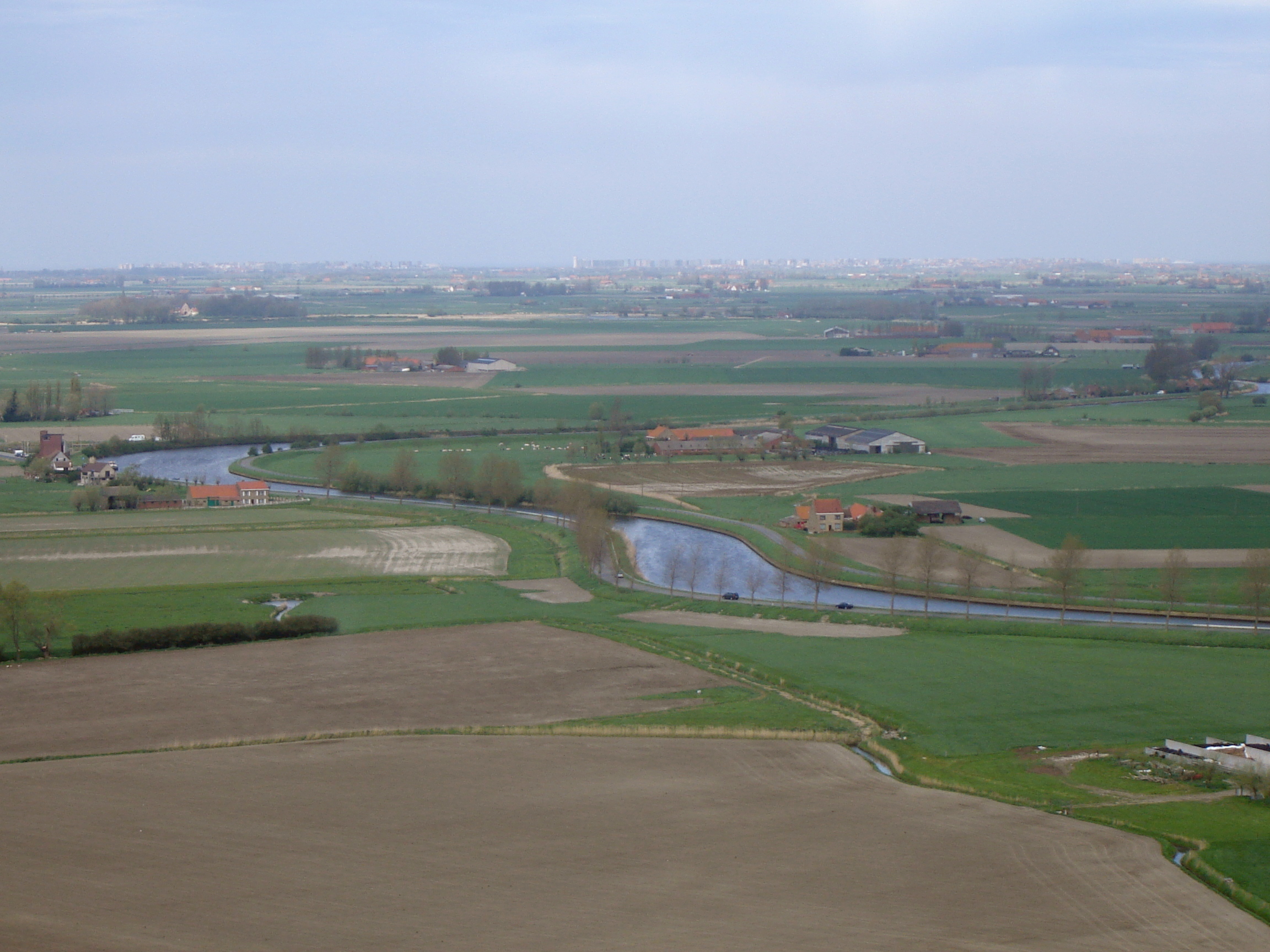 View on the West Flemish polders, seen from the IJzertoren tower in Diksmuide. In the middle the river IJzer (Yser). On the horizon the high-rise buildings along the Belgian coastline.