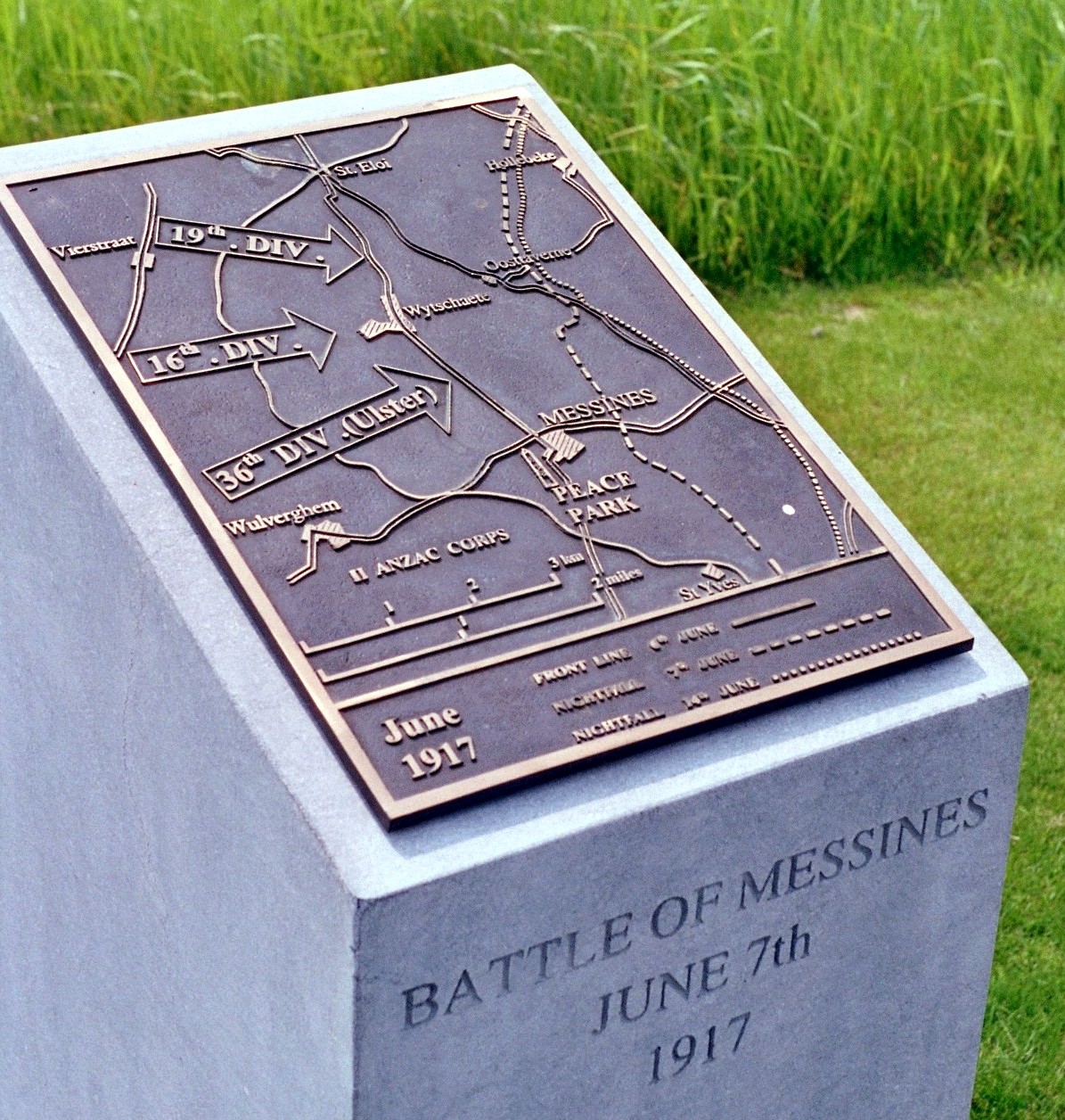 An elevated bronze plaque showing the direction of assault at the outset of the Battle of Messines in June 1917 in which the two voluntary Irish divisions, the 36th (Ulster) Division and the 16th (Irish) Division, played a decisive role. The plaque stands in the grounds of the Island of Ireland Peace Park, Messines, Belgium.