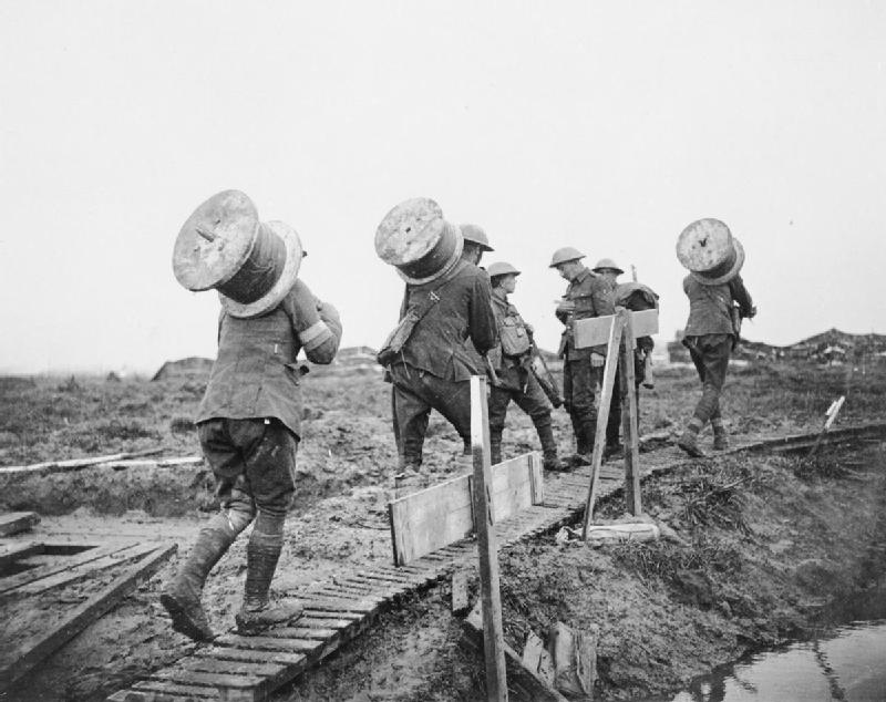 Battle of Poelcappelle 9 October 1917 : Royal Engineers taking drums of telephone wire along a duck board path up to the front between Pilckem and Langemarck.