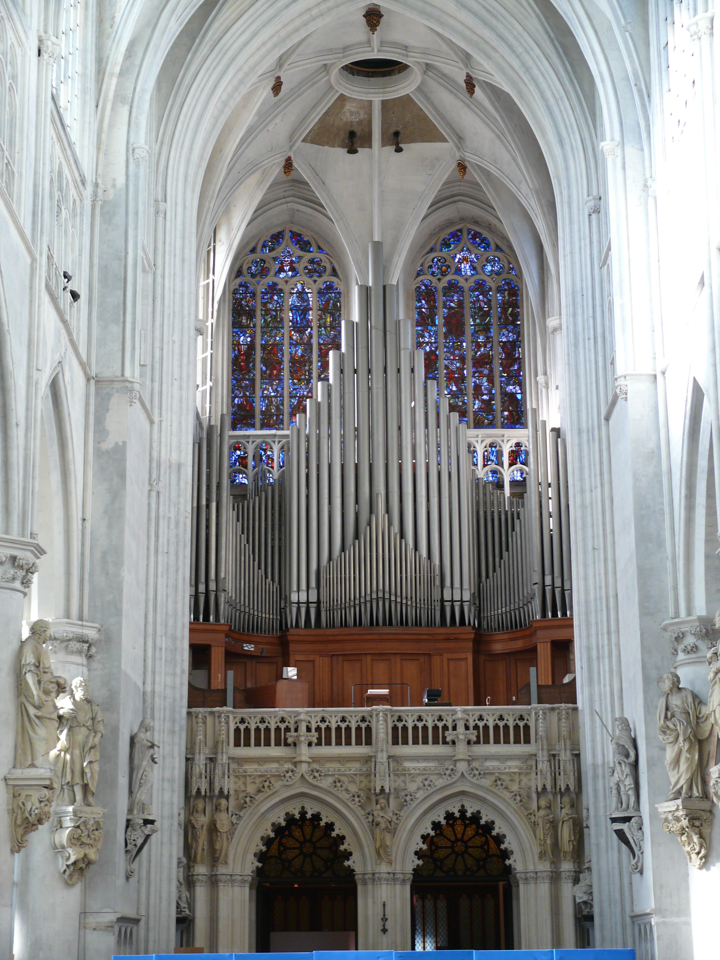 The  rood screen under the tower of St-Rumbold's Cathedral in Mechelen (Belgium) is in Gothic Revival style. It was added in 1854 according to the plans of architect Leo Suys, to place the organ at the back of the church. The organ itself was built in 1958 after designs by the organist Flor Peeters. It consists of 6606 organ pipes.
The statues along the sides in the aisle are tose of the apostles by Lucas Faydherbe.