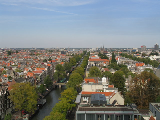Panoramic (?) view of Amsterdam, taken from the Westerkerk church tower, facing north. On the foreground is the famous en:Anne Frank house, which is now a museum.
Photograph taken by Stephane D'Alu in September 2003.