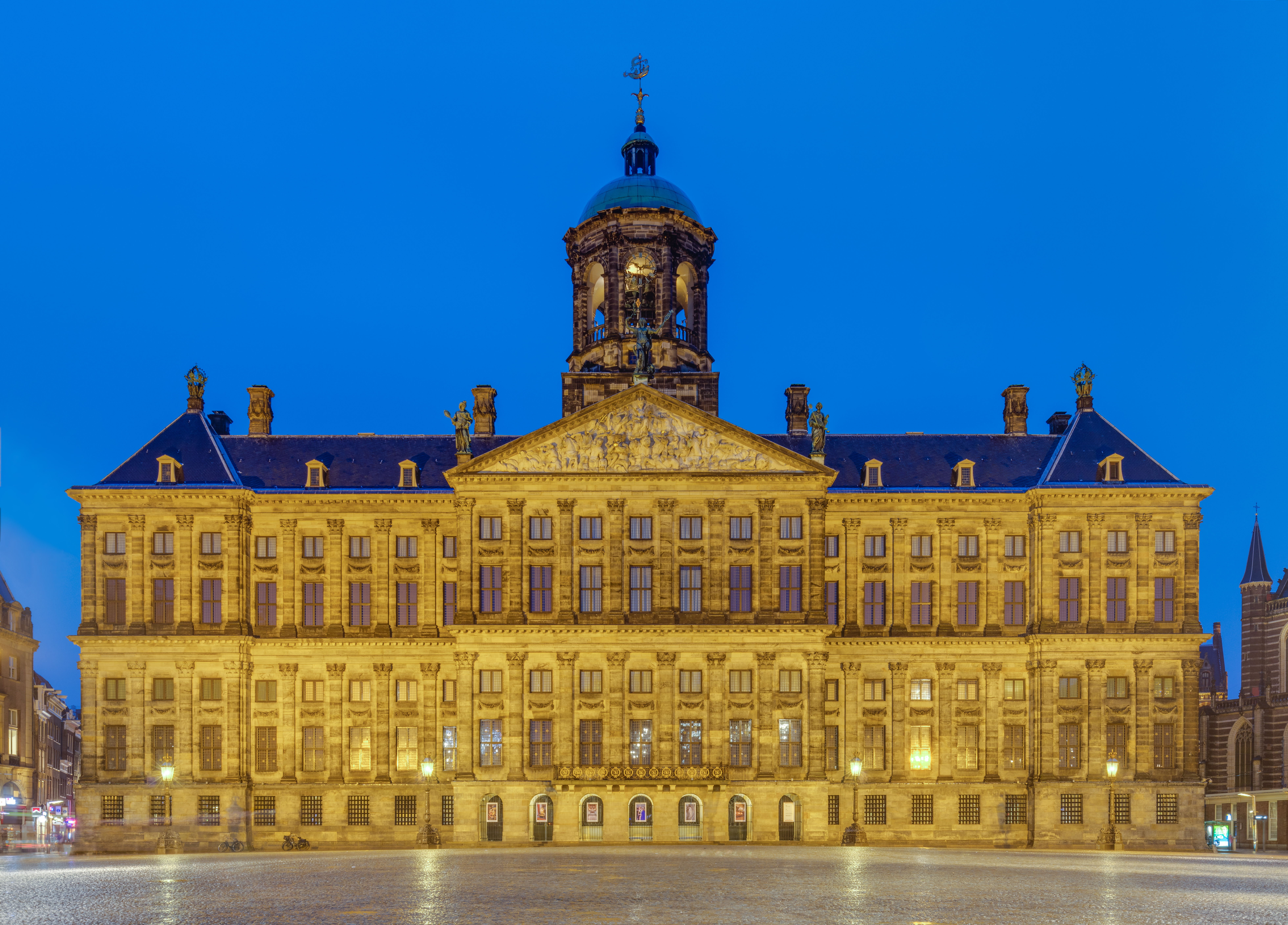 Blue hour view of front of the Royal Palace, Amsterdam, Netherlands. The palace was built as a city hall during the Dutch Golden Age and opened in 1655. The building became the royal palace of King Louis Napoleon and later of the Dutch Royal House. Currently it is one of the 3 palaces at the disposal of the monarch.