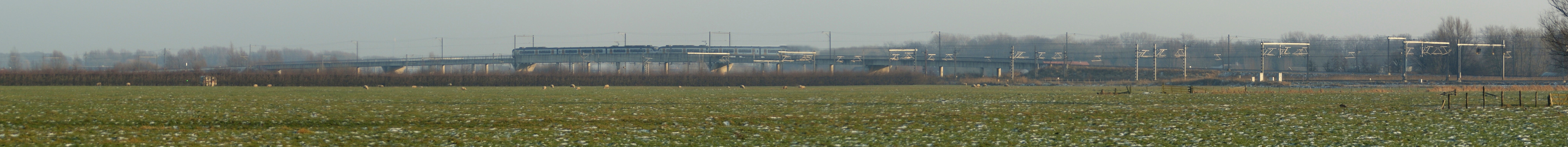 Panorama of the railway flyover north of Harmelen in the Netherlands. This flyover was built in the 1990s. In 1962, the Harmelen train disaster took place at the site of the flyover. This is a stitching of five separate photos, using Autostitch. This causes the train going from left to right to be blurred at the right end. If needed, I've got a version without a train. I increased the contrast slightly.