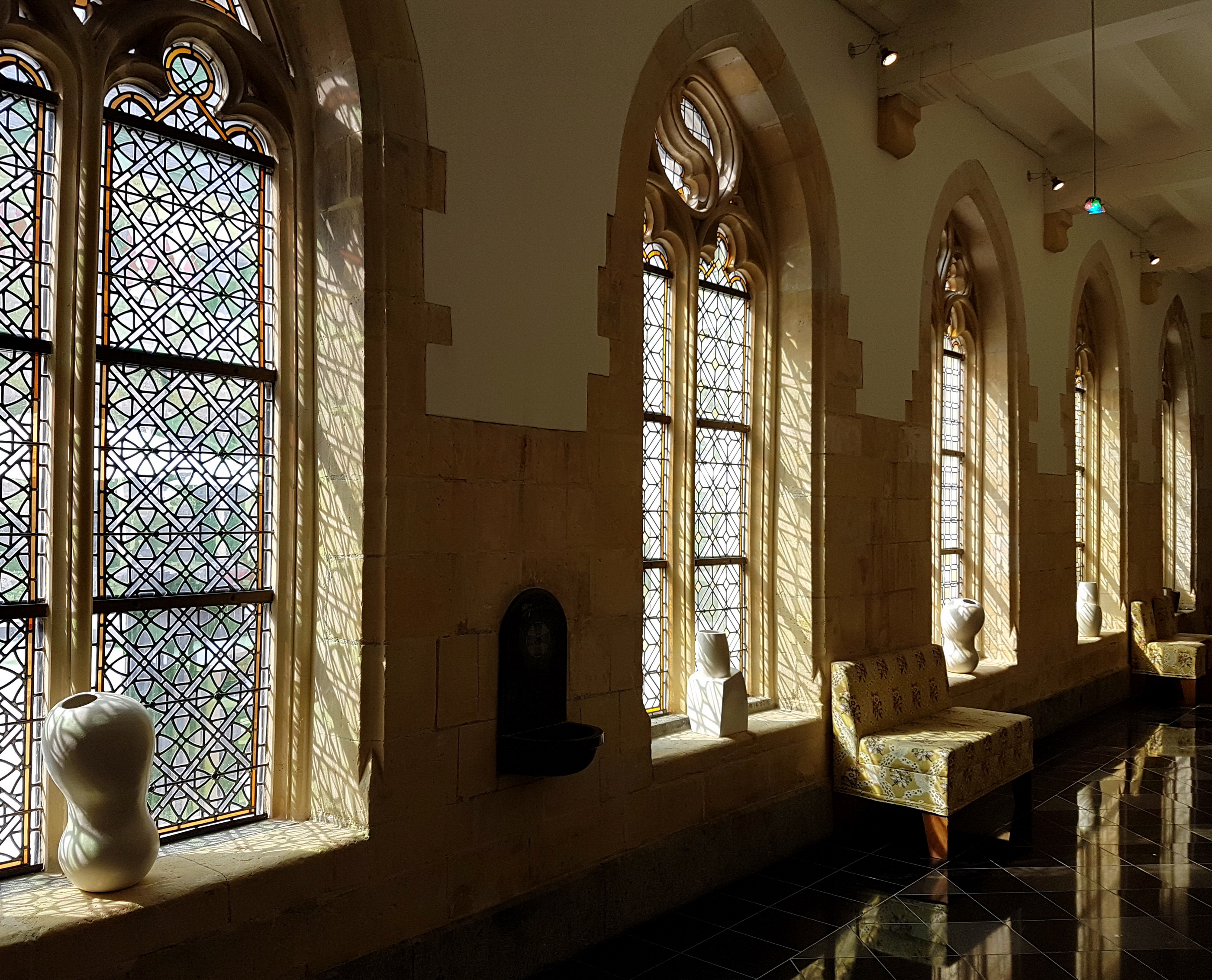 View of the east corridor of the cloisters of the Kruisherenklooster in Maastricht, the Netherlands. The Gothic Monastery of the Crutched Friars dates from the 15th century and in 2005 was converted into a luxury hotel, the Kruisherenhotel. The cloisters were originally partly open towards the cloister yard. The leaded-glass windows were possibly designed by Pierre Cuypers.