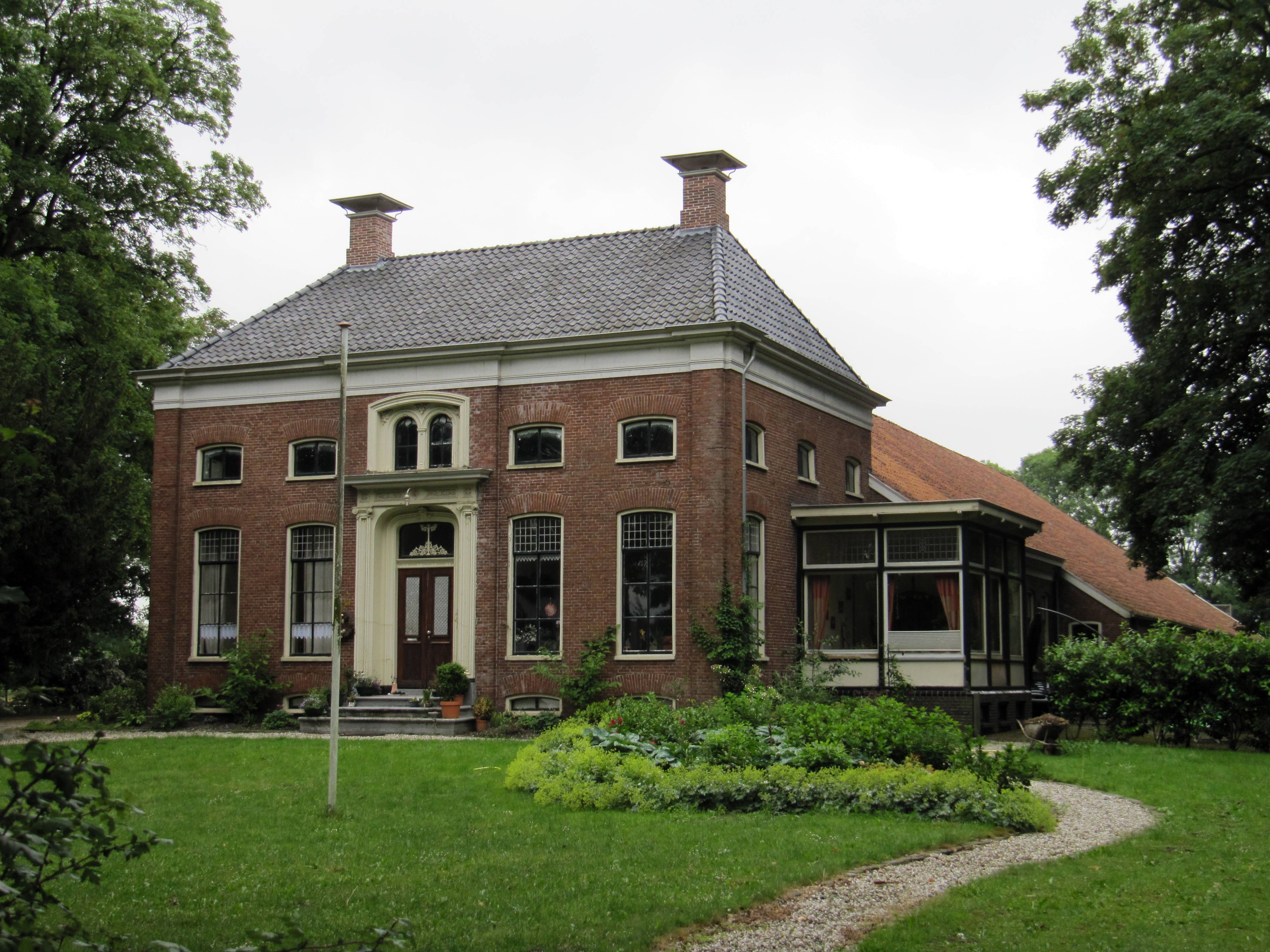 Oldambster dwarshuisboerderij in eclectische stijl gebouwd in 1872. De entree bevindt zich in het middenrisaliet van de voorgevel en bestaat uit twee houten paneeldeuren waarin gietijzeren roosters met bovenlicht met afgeronde hoeken waarin een gietijzeren levensboom; gepleisterde omlijsting van pilasters met Ionisch kapiteel en kroonlijst.