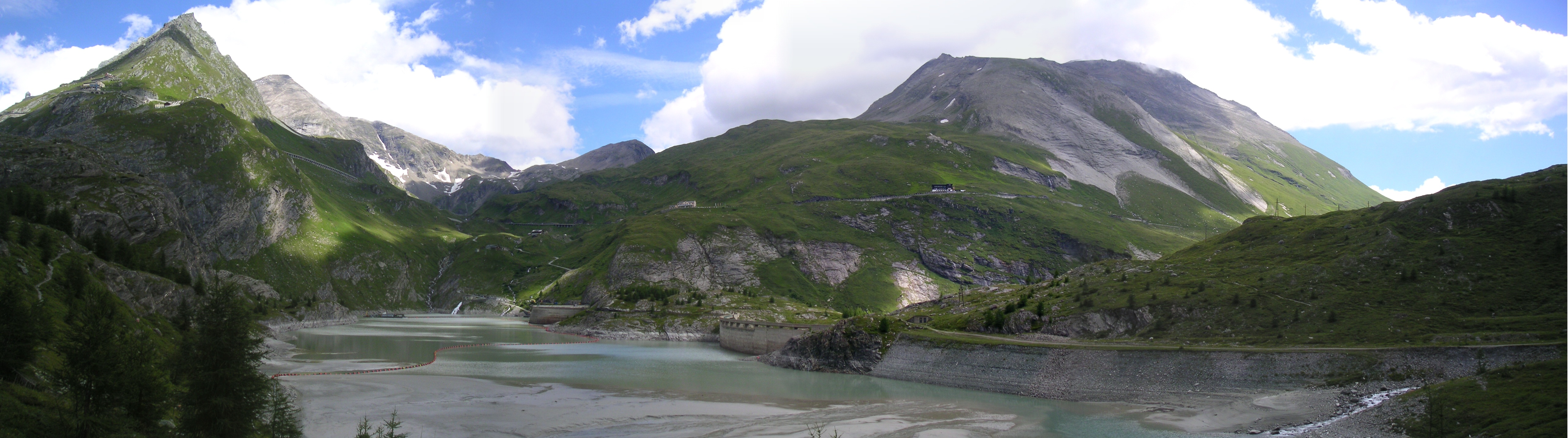 The Grossglockner High Alpine Road and its surroundings. The road descends over bridges across the left peak, passing along the center buildings, and then winding back downhill at the end of the lake, to follow along the right bank.)