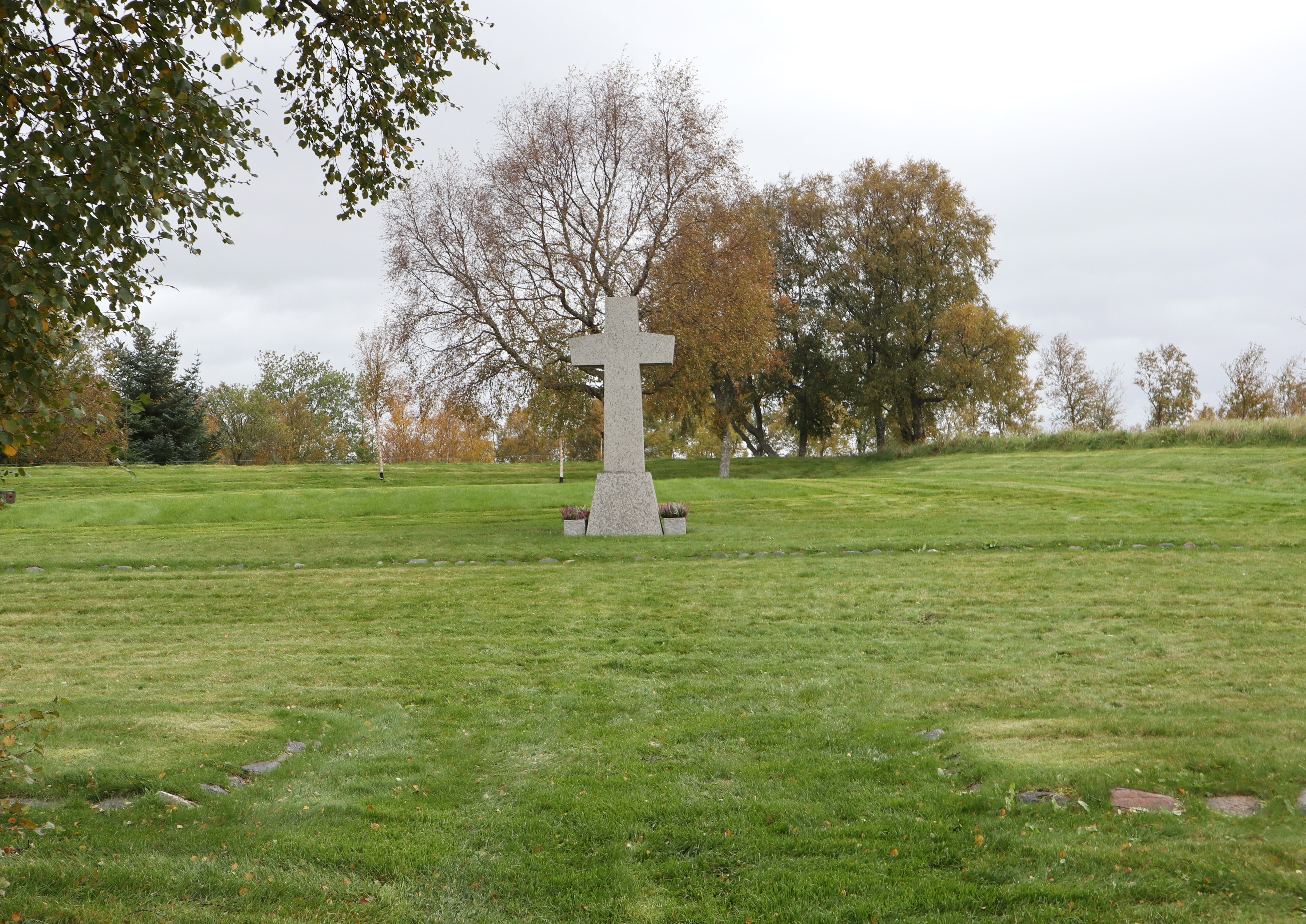 Green gras and a cross of grey stone.