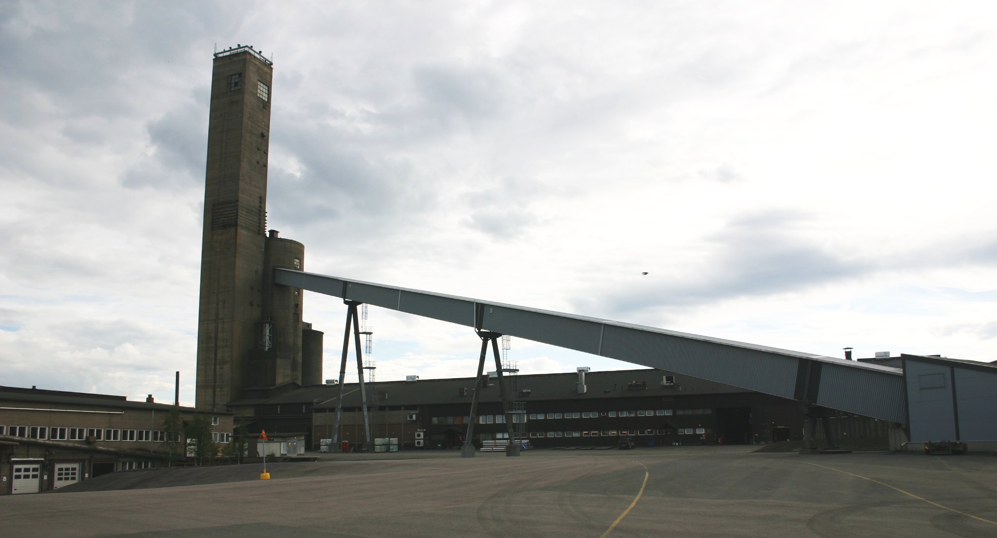 Picture of Pyhäsalmi mine area in Pyhäjärvi, Finland, showing the old tower and other buildings, including ore mill facility behind the ore conveyor.
