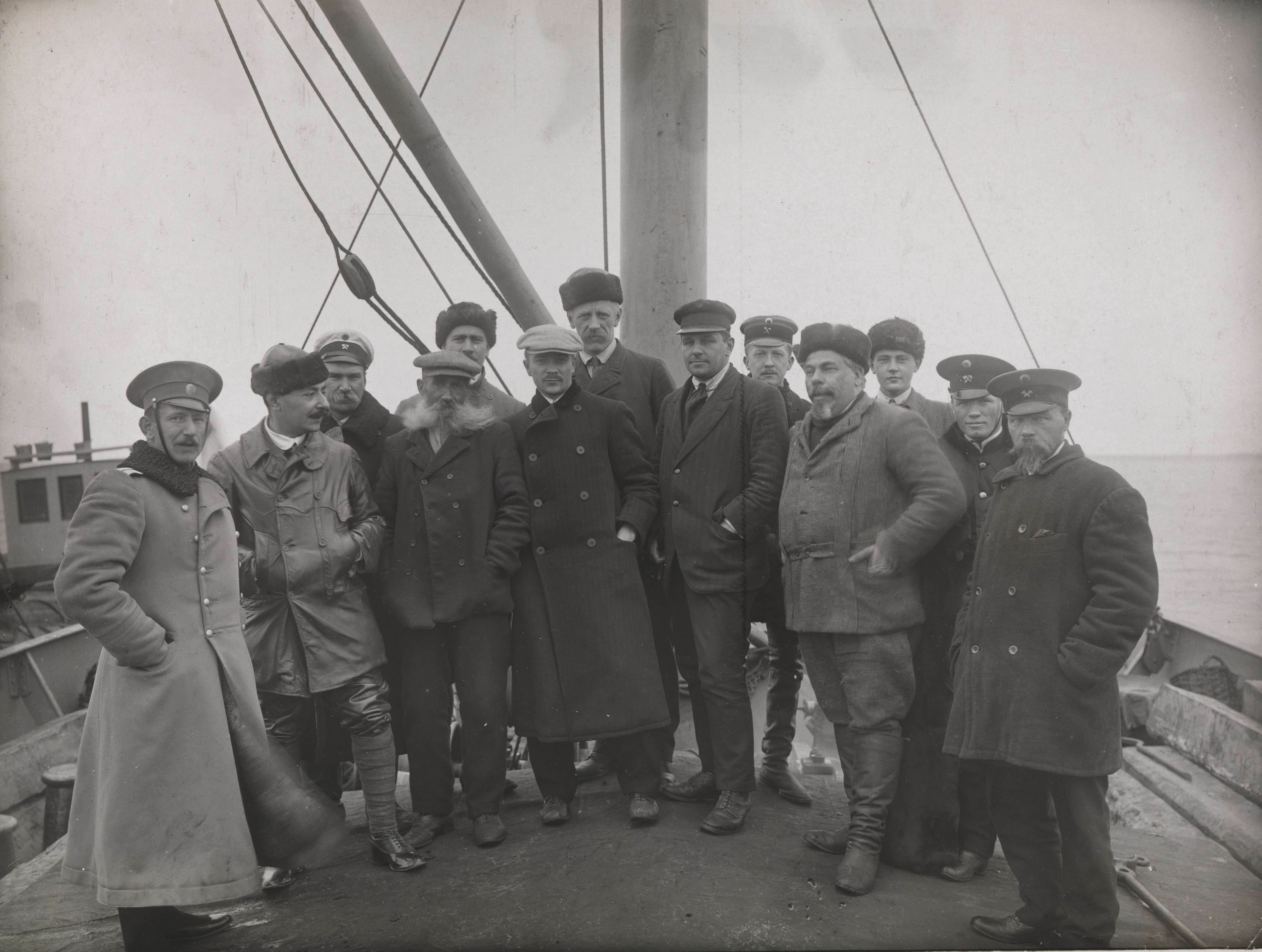 Meeting with officers from the Russian barges at the mouth of the Yenisei River. This was the end of the sea travel to Siberia. Among the people gathered: the crew from the «Correct», a Russian captain from the barge «Turukhansk», and the customs officers. Second from the left, Josef Gregorievitsj Loris-Melikov (secretary at the Russian legation in Norway); fourth for the left the ice pilot Hans Christian Johansen (Johannesen ); behind him, fifth from the left Jonas Lied, sixth from the left probably is Gunnar Christiansen, Lied's managing clerk; seventh from the left Fridtjof Nansen; eighth from the left Capt. Johan Samuelsen; tenth from the left, Stephan Vasilievitsj Vostrotin (gold mine owner from Yeniseisk). After a few days stay, Nansen, Loris-Melikov and Vostrotin continued their journey up the Yenisei River. The ship «Correct» with J. Lied and G. Christiansen unloaded their cargo from barges, and returned to Kristiania. One of the pictures from the journey to Siberia between Aug. 2 and Oct. 26, 1913. Fridtjof Nansen started his trans-Siberian travel on a freighter from Oslo to Yenisei. The journey went through parts of the Northeast Passage, which was to be opened as a shorter trading connection between Western Europe and the Far East.
