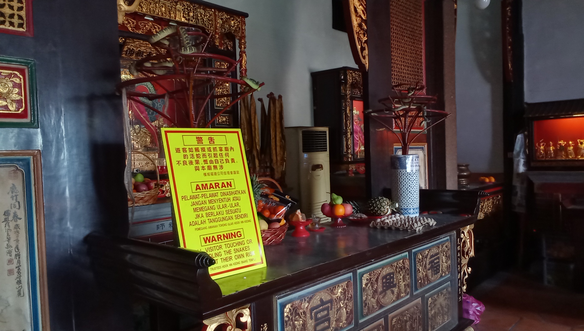 This is the center of the interior of the main building of the Snake Temple. Behind, there is an altar. In front, there are various offerings, two stands with three snakes on each, and a warning that anyone touching the snakes does so at their own risk. Yes, the snakes are real. Yes, I touched the snakes.