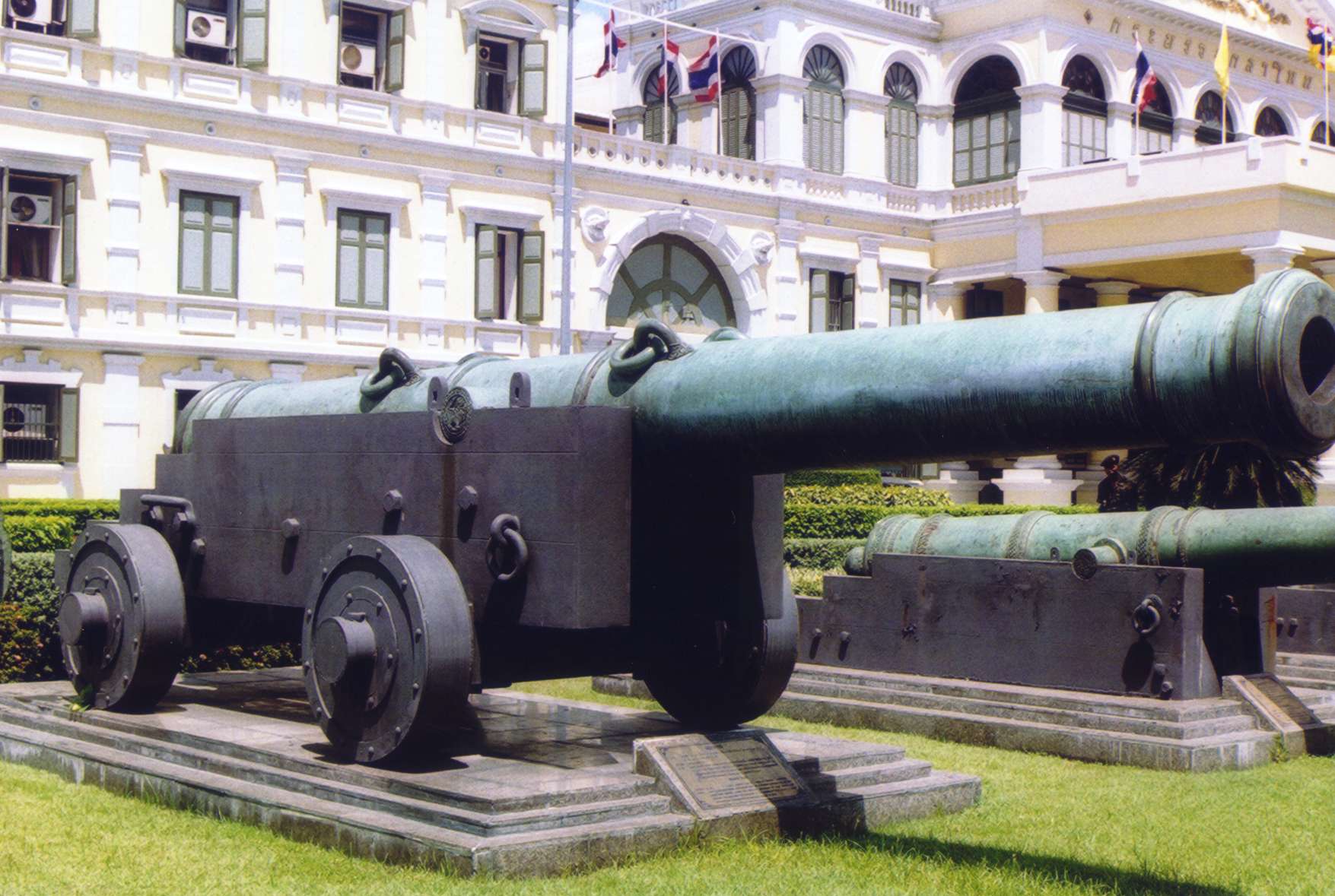One of the cannons in front of the Ministry of Defence, Bangkok, Thailand. Photo taken before the re-alignment of the canons in 2004, so it points toward Wat Phra Kaew, not to the south like it does now.
The canon depicted may be Phraya Tani (พญาตานี), or the cannon cast to be a replica of it. (can anyone identify it).

Photo taken by User:Ahoerstemeier in 2003.