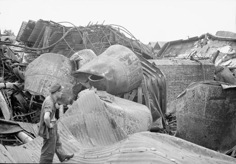 A Royal Air Force motor transport driver surveys damage caused by Allied bombing at Singapore docks.
