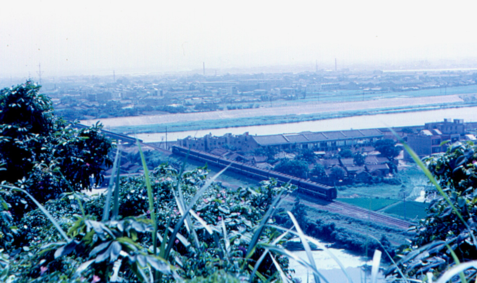 Looking southwest from Grand Hotel grounds, to part of Taipei, Keelung River, and a railroad [Note: TRA Tamsui Line].  This photo is geotagged with the camera location.
