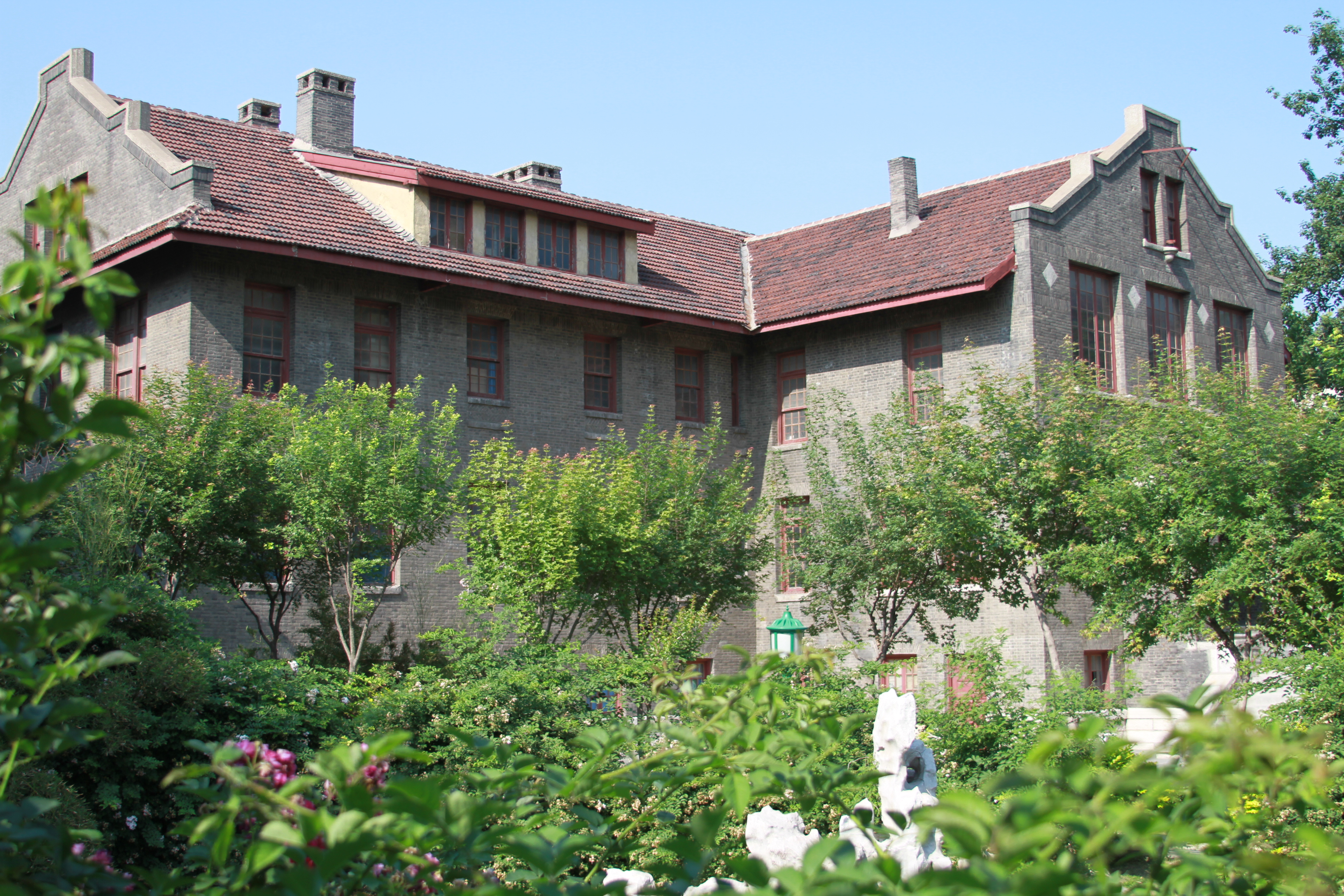 Photograph of one of the main buildings of the Weihsien Internment Camp, Weifang, Shandong, China seen from the adjacent park.
