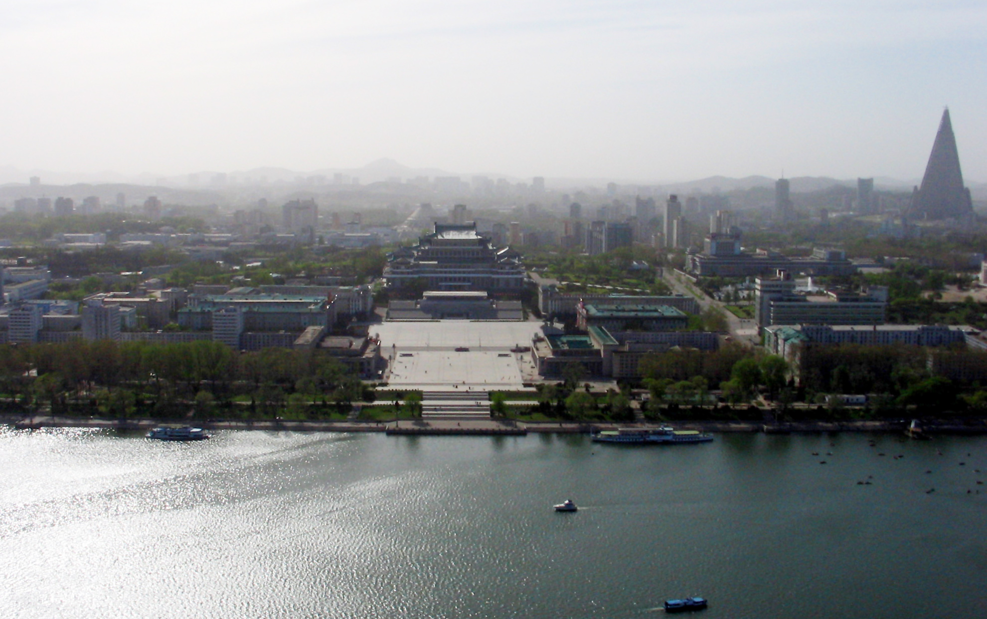 Pyongyang, North Korea as seen from the Juche Tower, facing west across the Taedong river. The large square in the centre is Kim Il-Sung Square; the large building behind it is the Grand People's Study House. The massive triangular building on the right of the photo is the Ryugyong Hotel.
The haze was due to forest fires near the China/Mongolia border, and is not the smog typical of large East Asian cities. (Photograph taken with a Canon PowerShot A85)