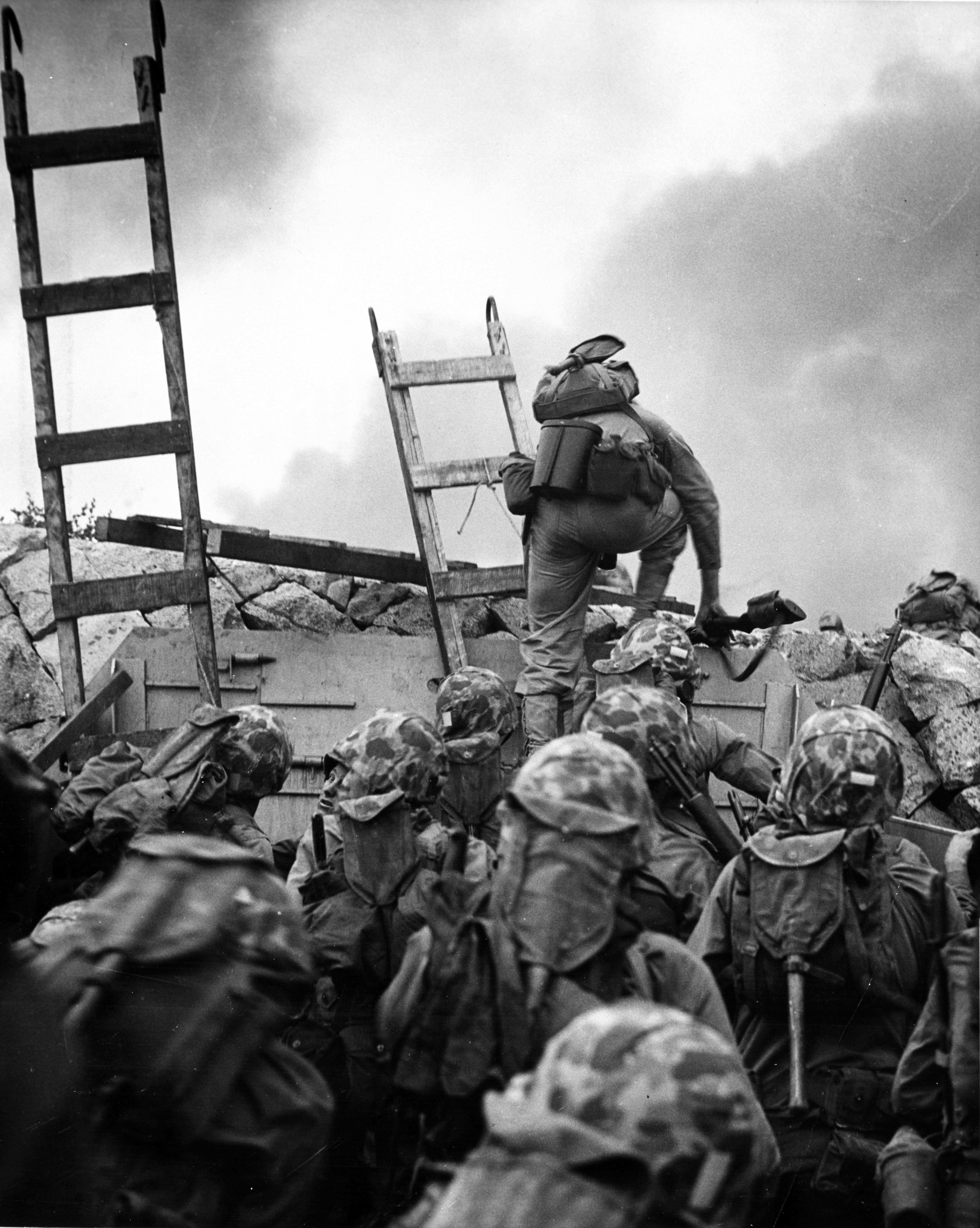 First Lieutenant Baldomero Lopez, USMC, leads the 3rd Platoon, Company A, 1st Battalion, 5th Marines over the seawall on the northern side of Red Beach, as the second assault wave lands, 15 September 1950, during the Inchon invasion. Wooden scaling ladders are in use to facilitate disembarkation from the LCVP that brought these men to the shore. Lt. Lopez was killed in action within a few minutes, while assaulting a North Korean bunker. Note M-1 Carbine carried by Lt. Lopez, M-1 Rifles of other Marines and details of the Marines' field gear. Photo number NH 96876.