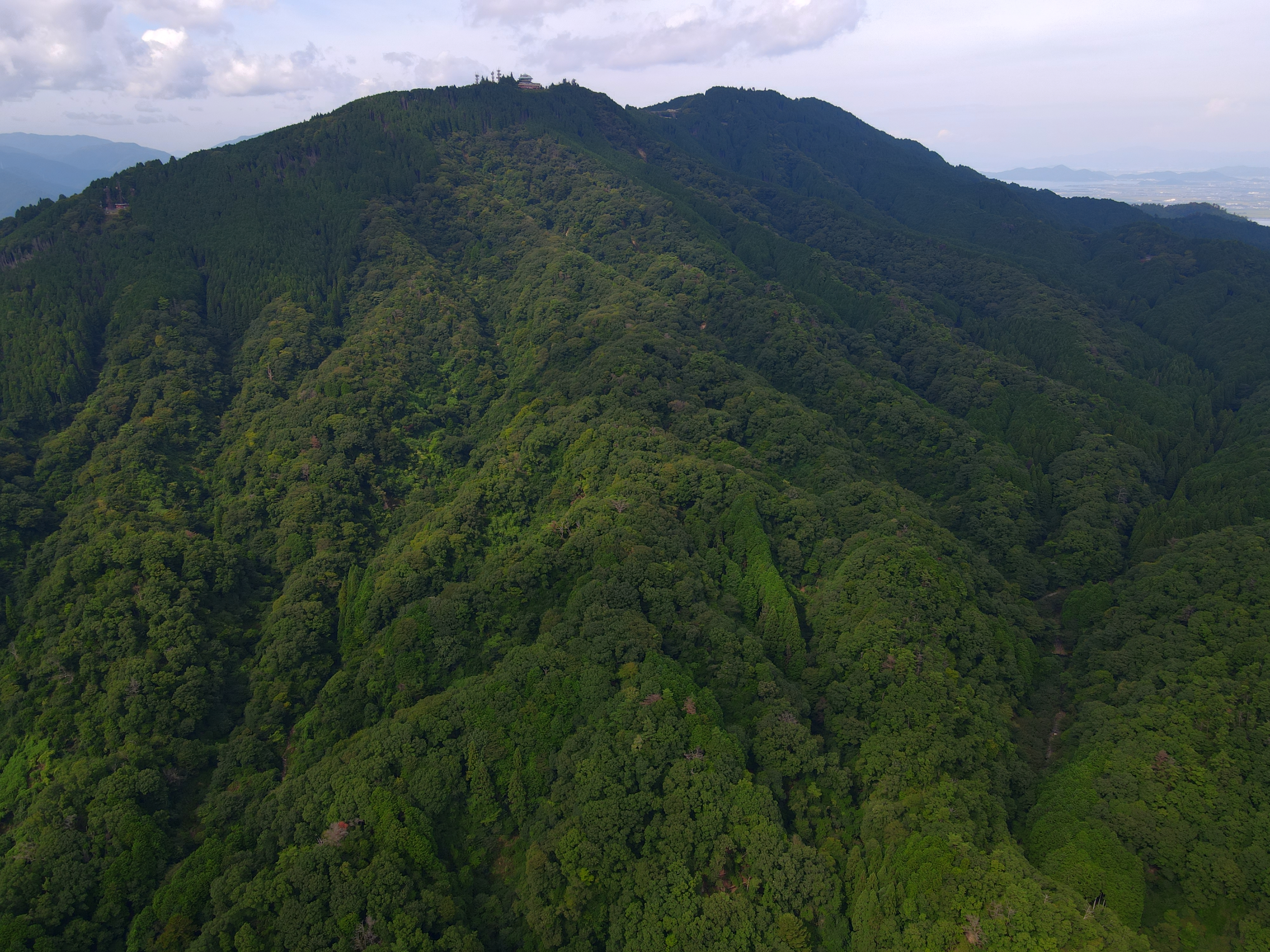 Aerial drone shot of the summit of Mount Hiei taken from the southwest, at 150 metres above ground level (as measured from the take-off point) using a DJI Mavic Air 2 drone, as 5 different exposure shots in AEB mode, and then manually merged into HDR using plateau weights, gamma response curve and Debevec model, along with Reinhard05 tonemap.