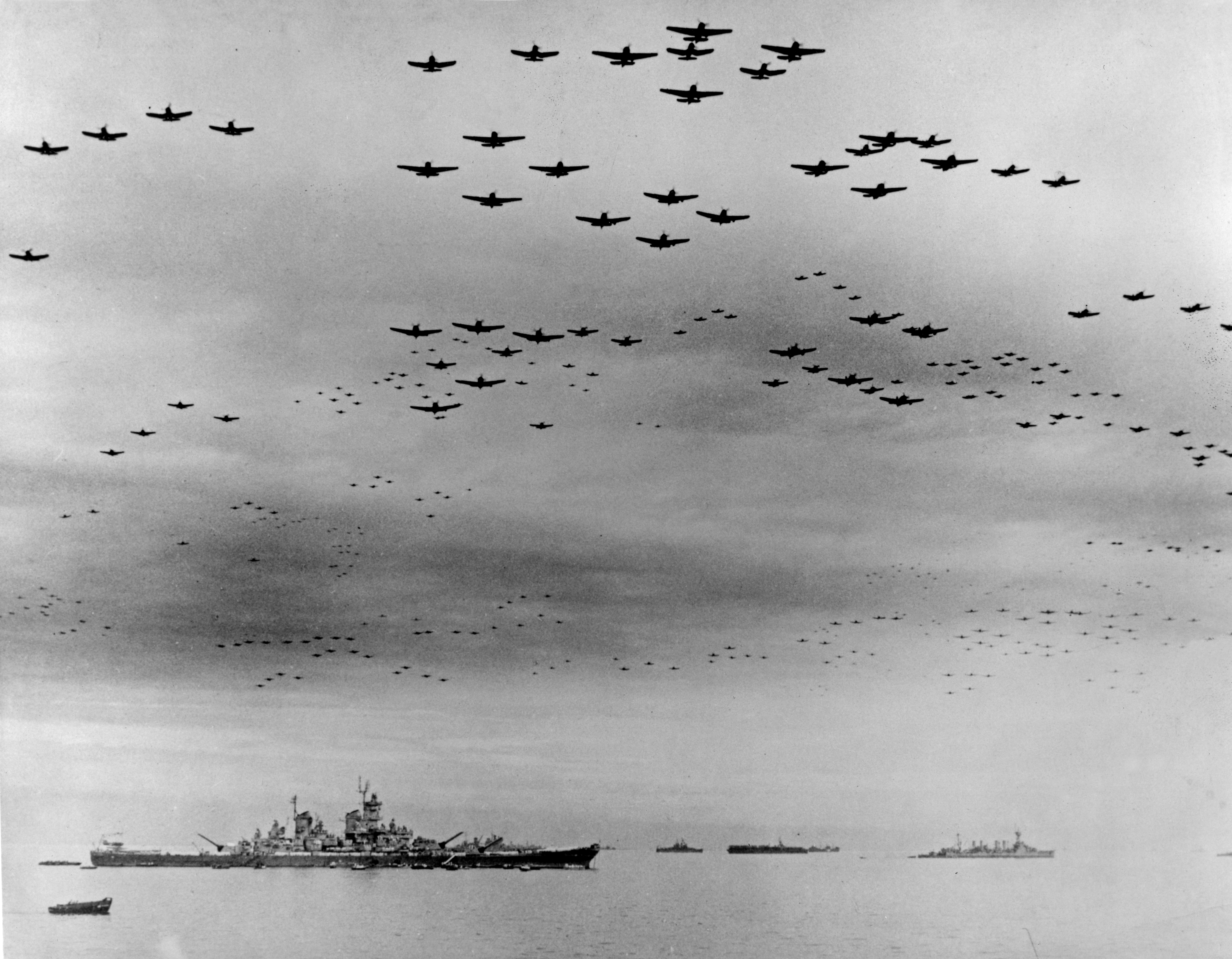 Surrender of Japan, 2 September 1945: U.S. Navy carrier planes fly in formation over the U.S. and British fleets in Tokyo Bay during surrender ceremonies. The battleship USS Missouri (BB-63), where the ceremonies took place, is at left. The light cruiser USS Detroit (CL-8) is in the right distance. Aircraft include Grumman TBM Avenger, Grumman F6F Hellcat, Curtiss SB2C Helldiver and Vought F4U Corsair types.