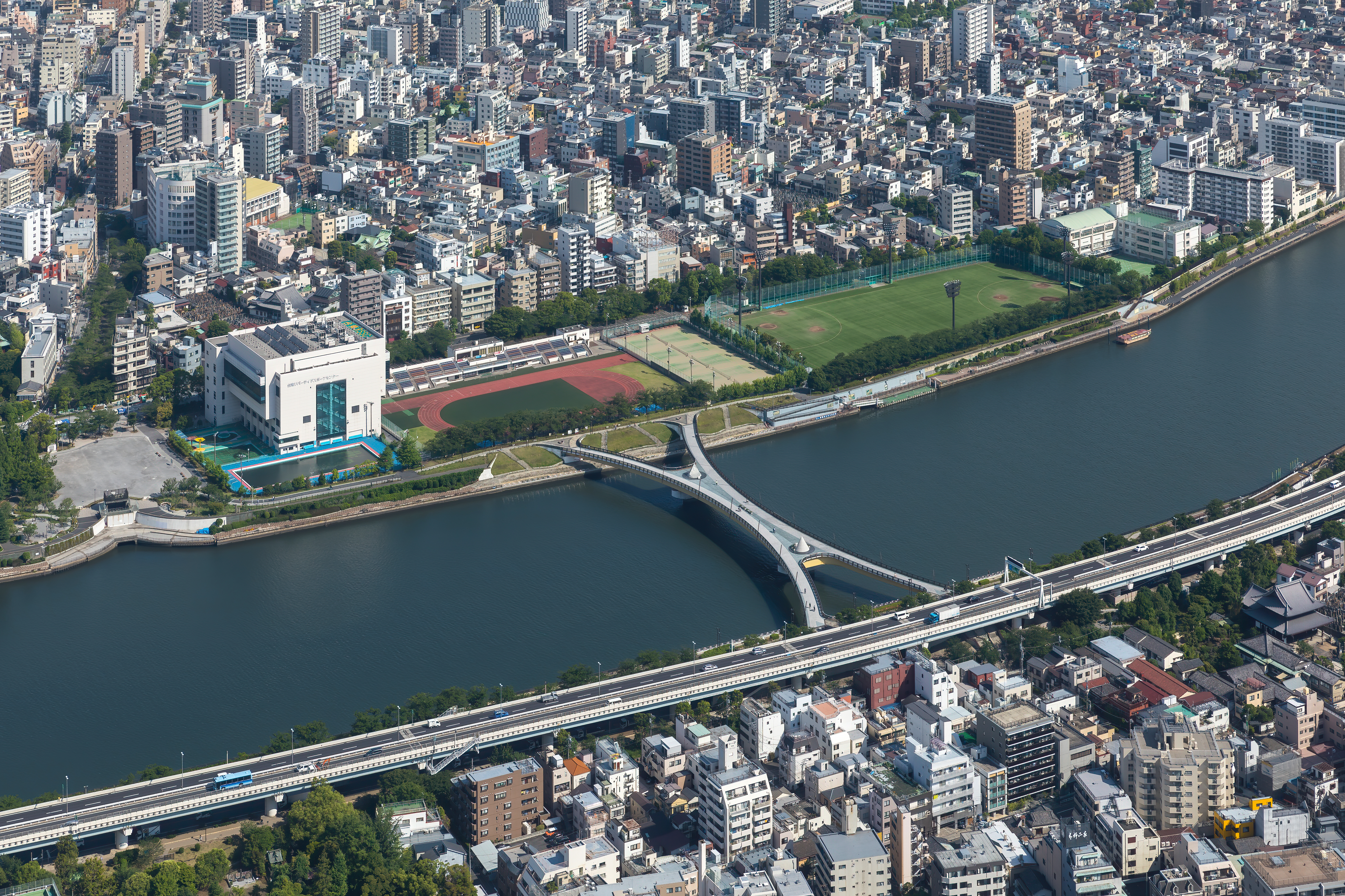 X-shaped pedestrian Sakura bridge over Sumida river, linking Sumida Park (Taitō ward) and Bokutei-dori Avenue (Sumida ward), seen from the tower Tokyo Skytree, Tokyo, Japan. The x-shaped bridge was designed with the intention of having people from four points on both sides, upstream and downstream, have an encounter midway.