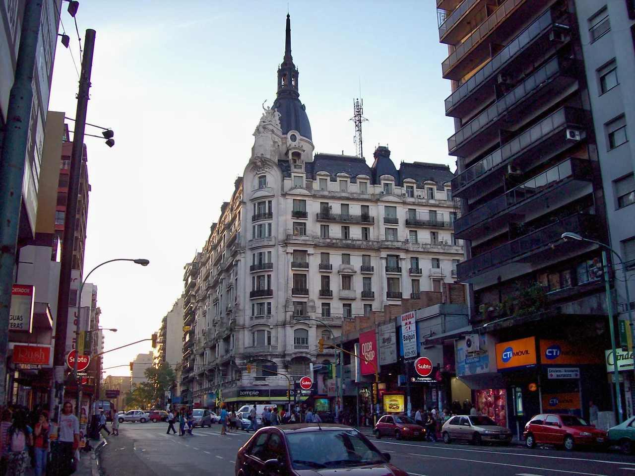 View of Corrientes Avenue and the Pueyrredón Avenue intersection, in the Balvanera section of Buenos Aires. The building in the center is the Caja Internacional Mutua de Pensiones ("International Mutual Pension Fund"), designed by Gastón Mallet and Jacques Dunant and completed in 1908.