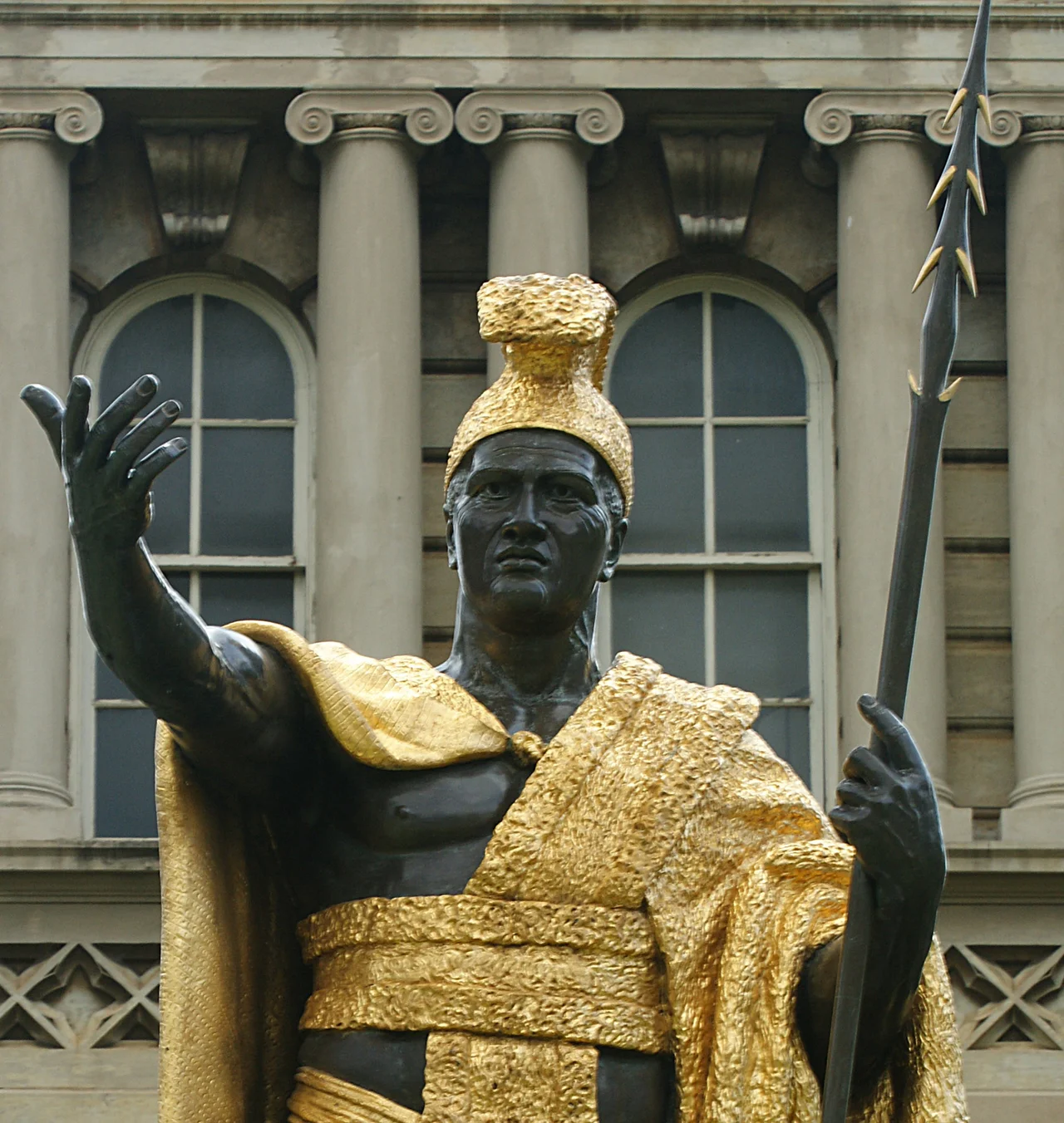 Statue of King Kamehameha I, standing in front of Ali'iolani Hale in Honolulu.  Cast: 1881, bronze with gold leaf.  Approx 8½ feet tall on a 10 foot concrete base. The pedestal has four bronze and gold leaf plaques with scenes from Kamehameha's life.  Sculptor: Thomas Ridgeway Gould (1818–1881).